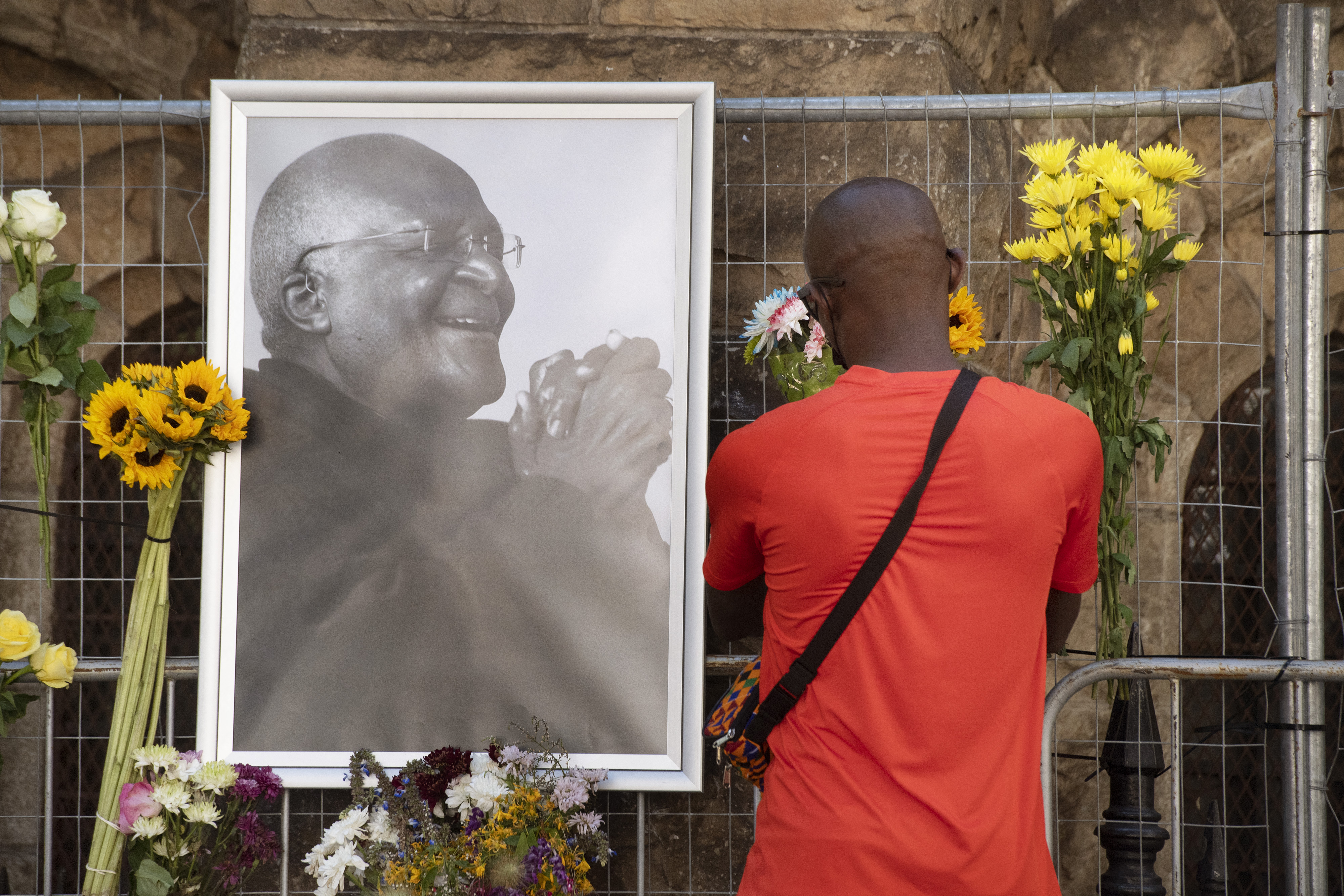 A mourner puts flowers on Wall of Remembrance for Archbishop Desmond Tutu in Cape Town