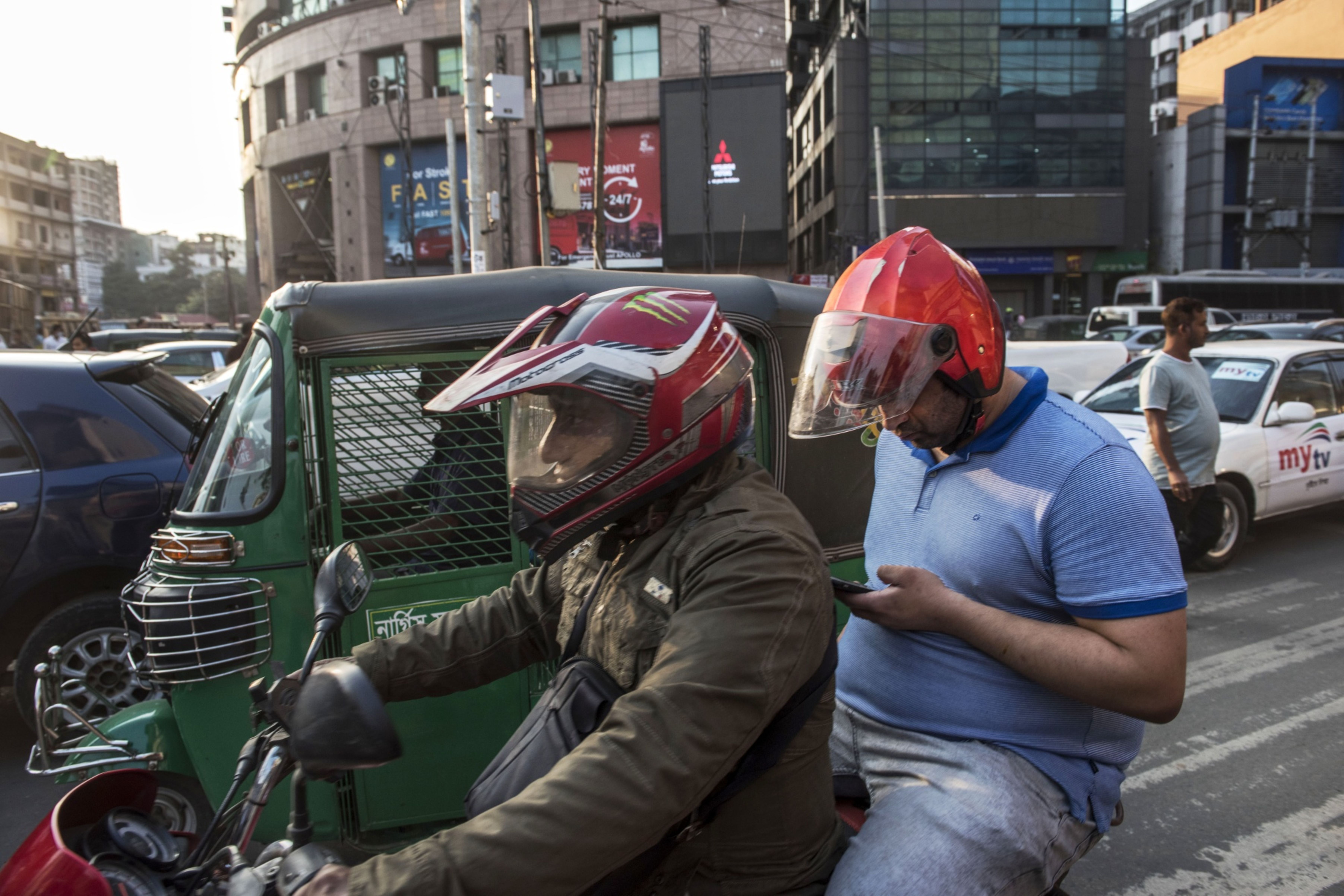 A motorcyclist and passenger sit in traffic in Dhaka, Bangladesh