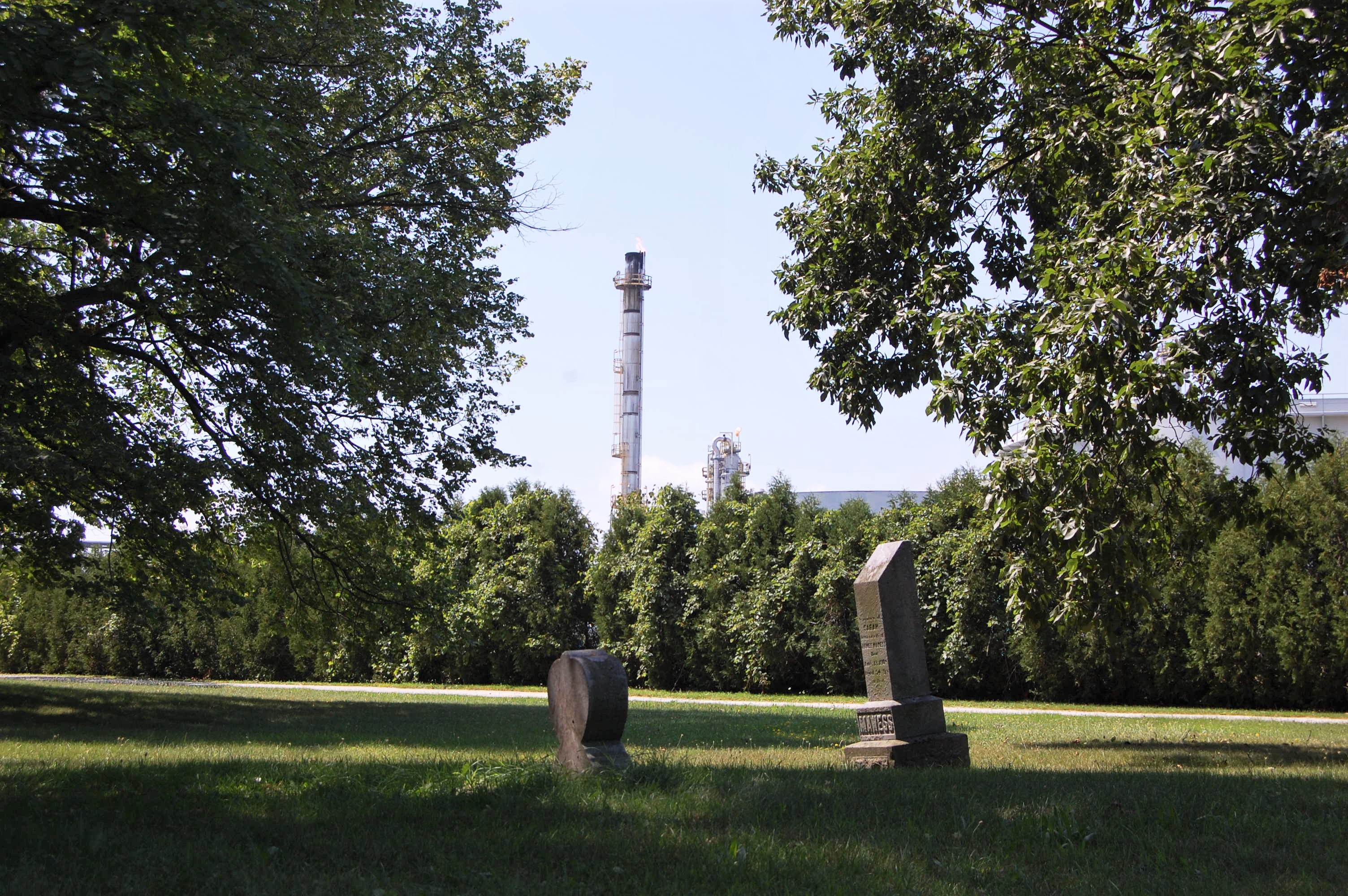 A gas flare can be seen in the background near a cemetery in Aamjiwnaang First Nation [Jillian Kestler-D'Amours/Al Jazeera]