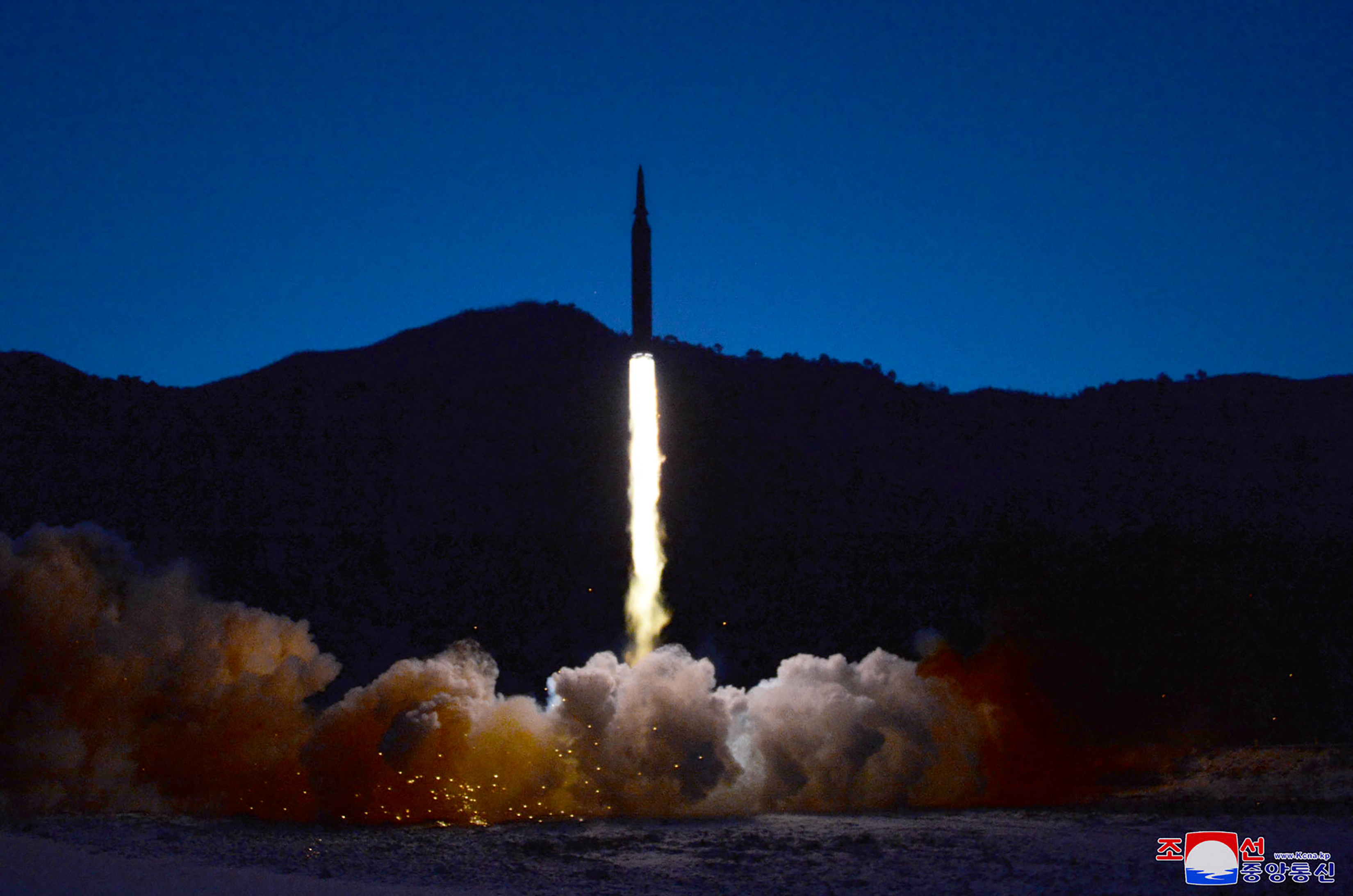 A missile launches into a dark sky in clouds of smoke