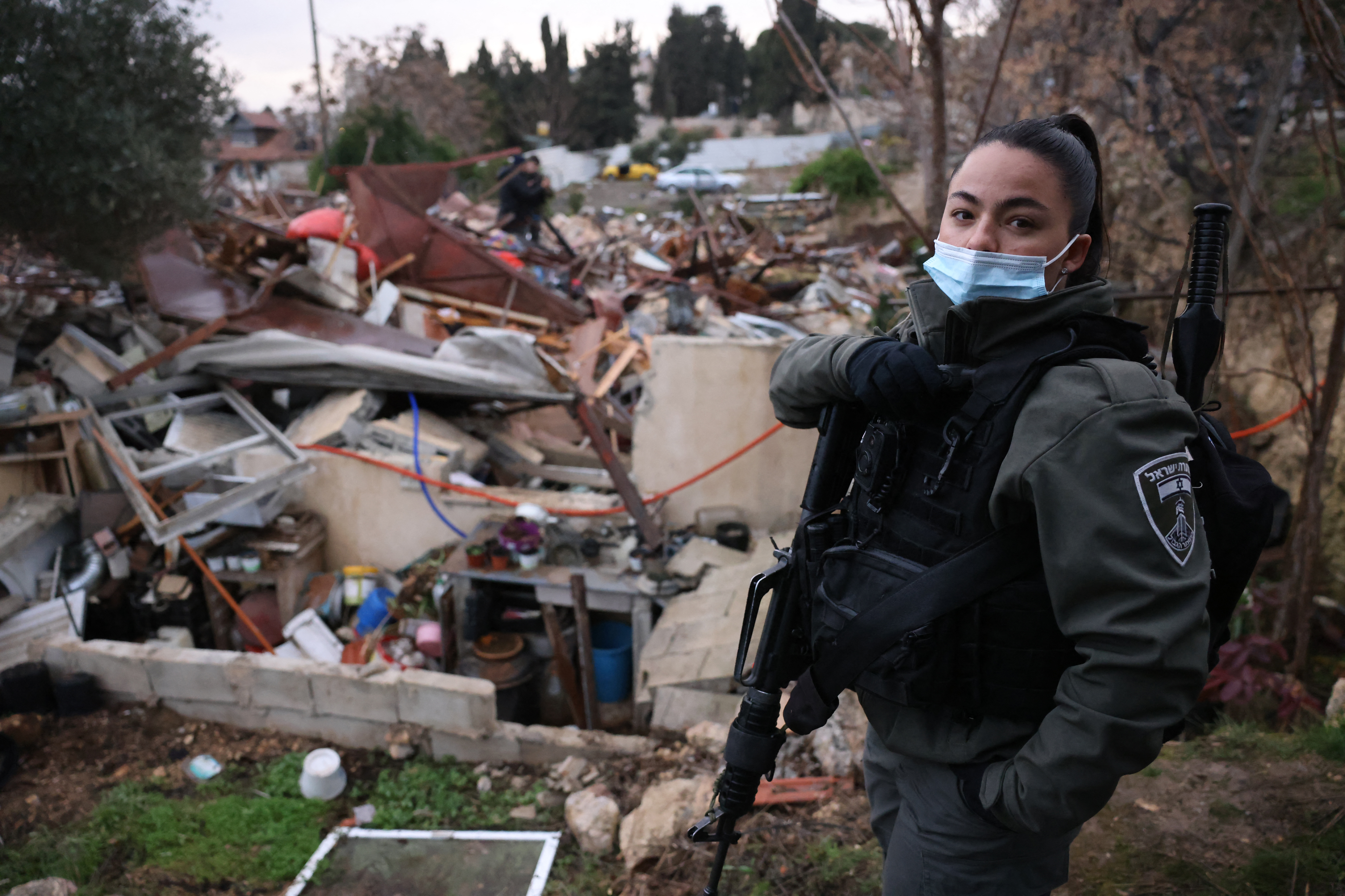A member of the Israeli forces stands by the ruins of a Palestinian house they demolished, in Sheikh Jarrah