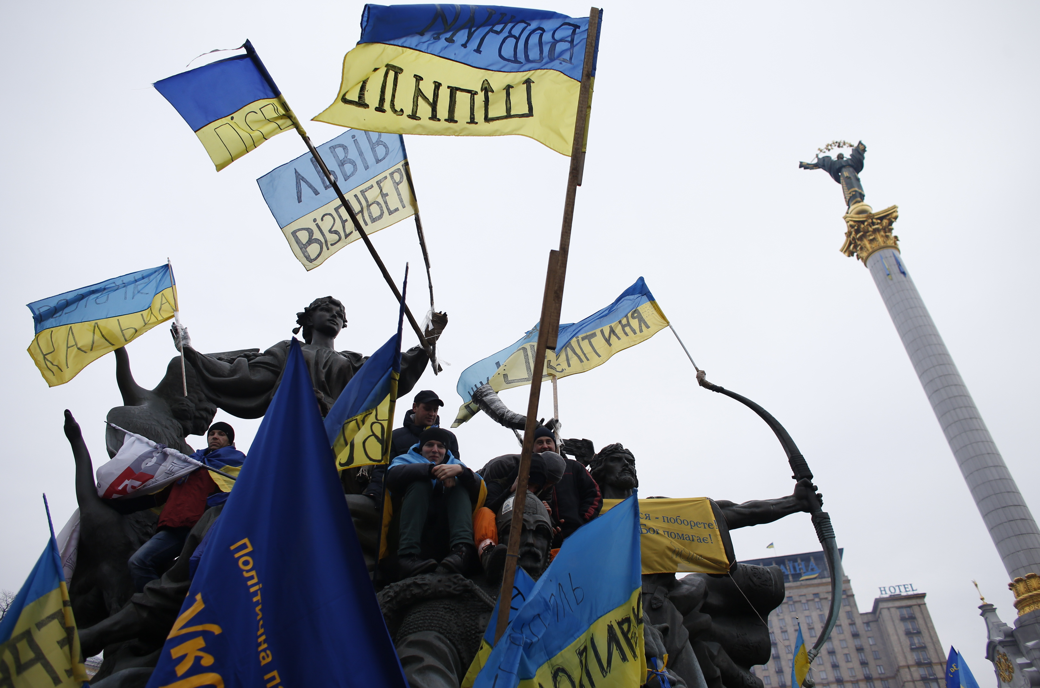 Pro-European integration protesters stand on a statue with Ukranian flags during a rally in Independence Square in Kiev December 15, 2013.
