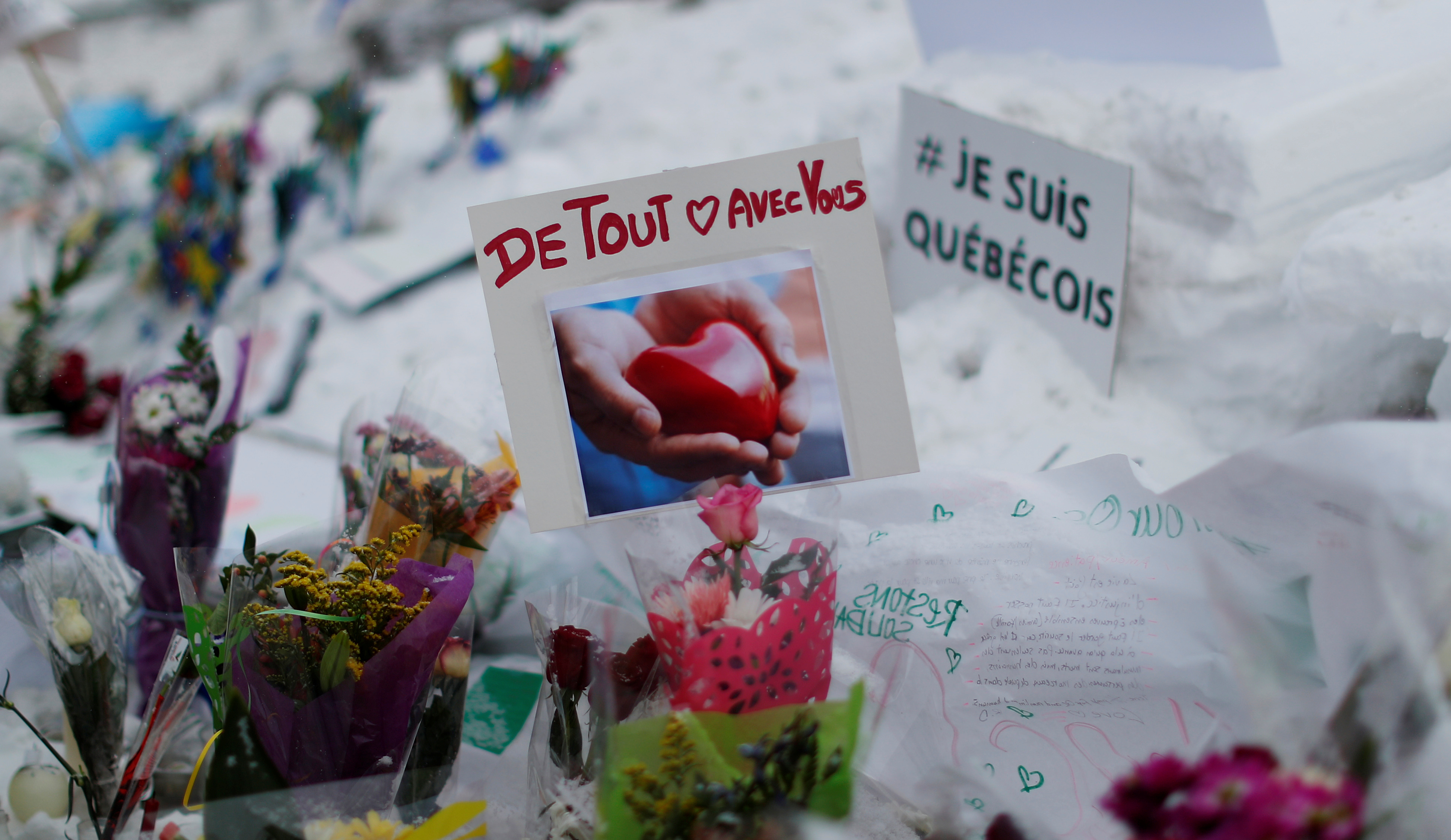 A sign reads 'With you with all our heart' at a memorial to the victims