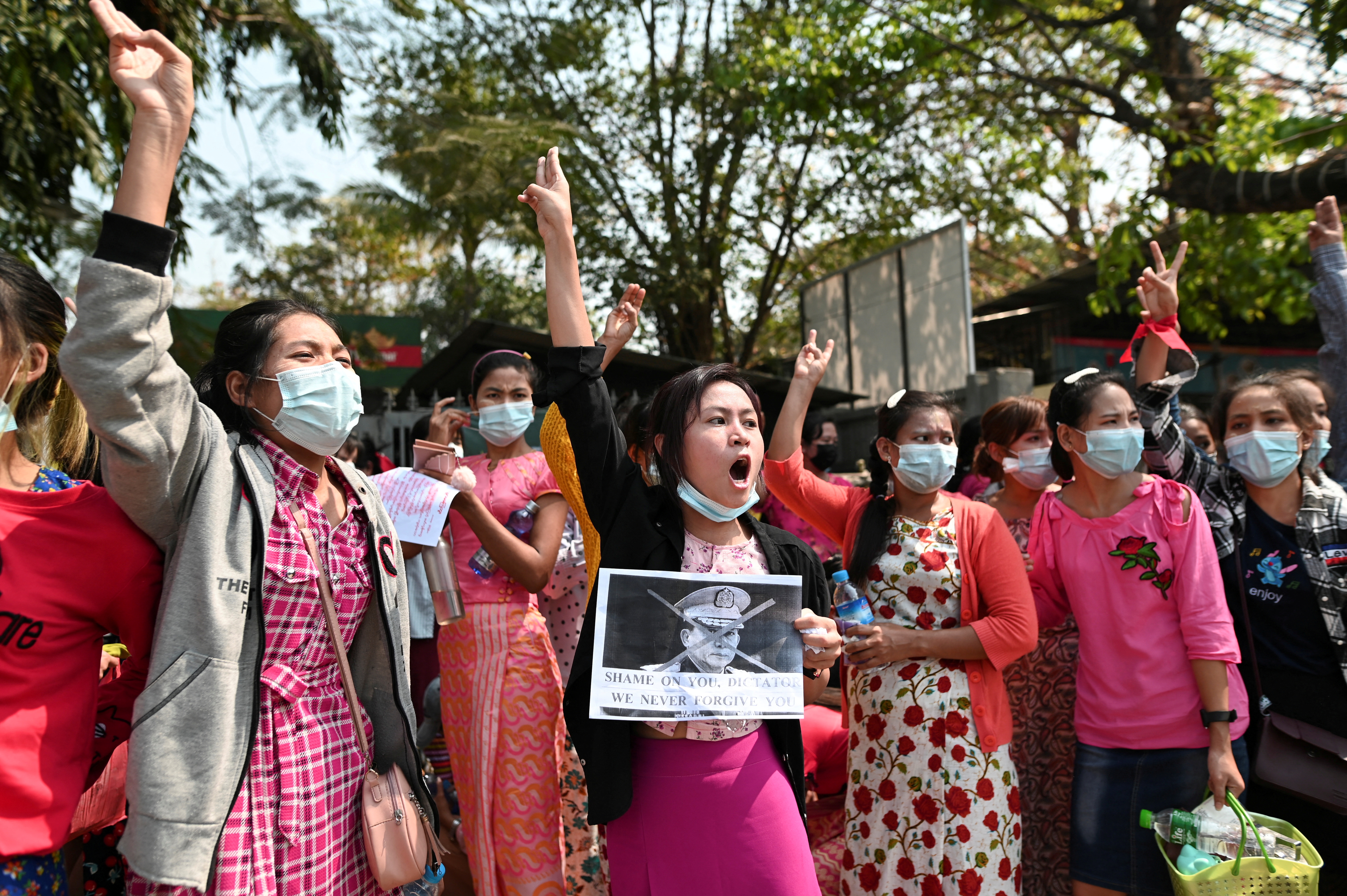 Demonstrators show the three-finger salute and hold a picture of Myanmar's army chief Min Aung Hlaing with his face crossed out during a protest against the military coup in Yangon, Myanmar.