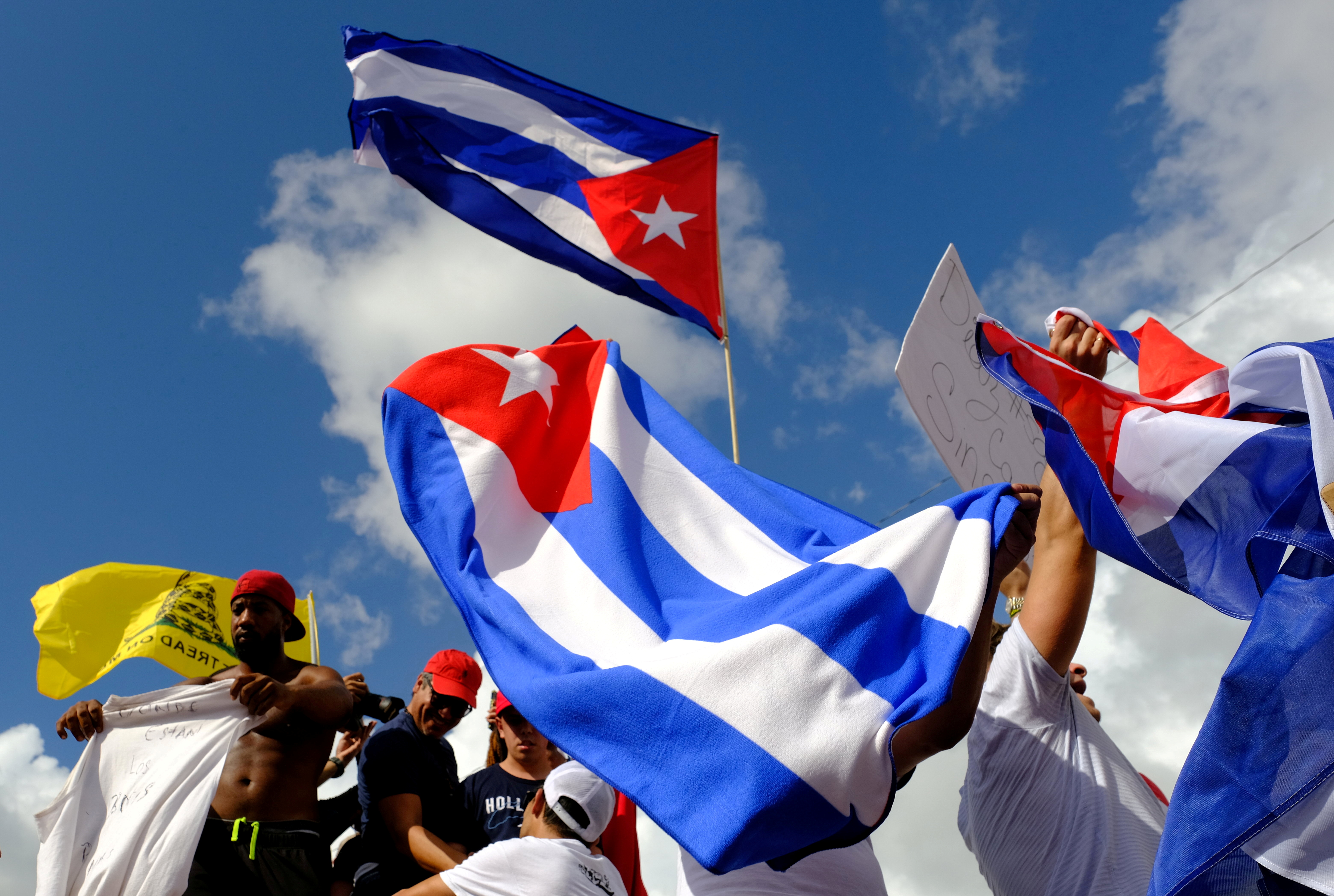 Protesters waving three Cuban flags