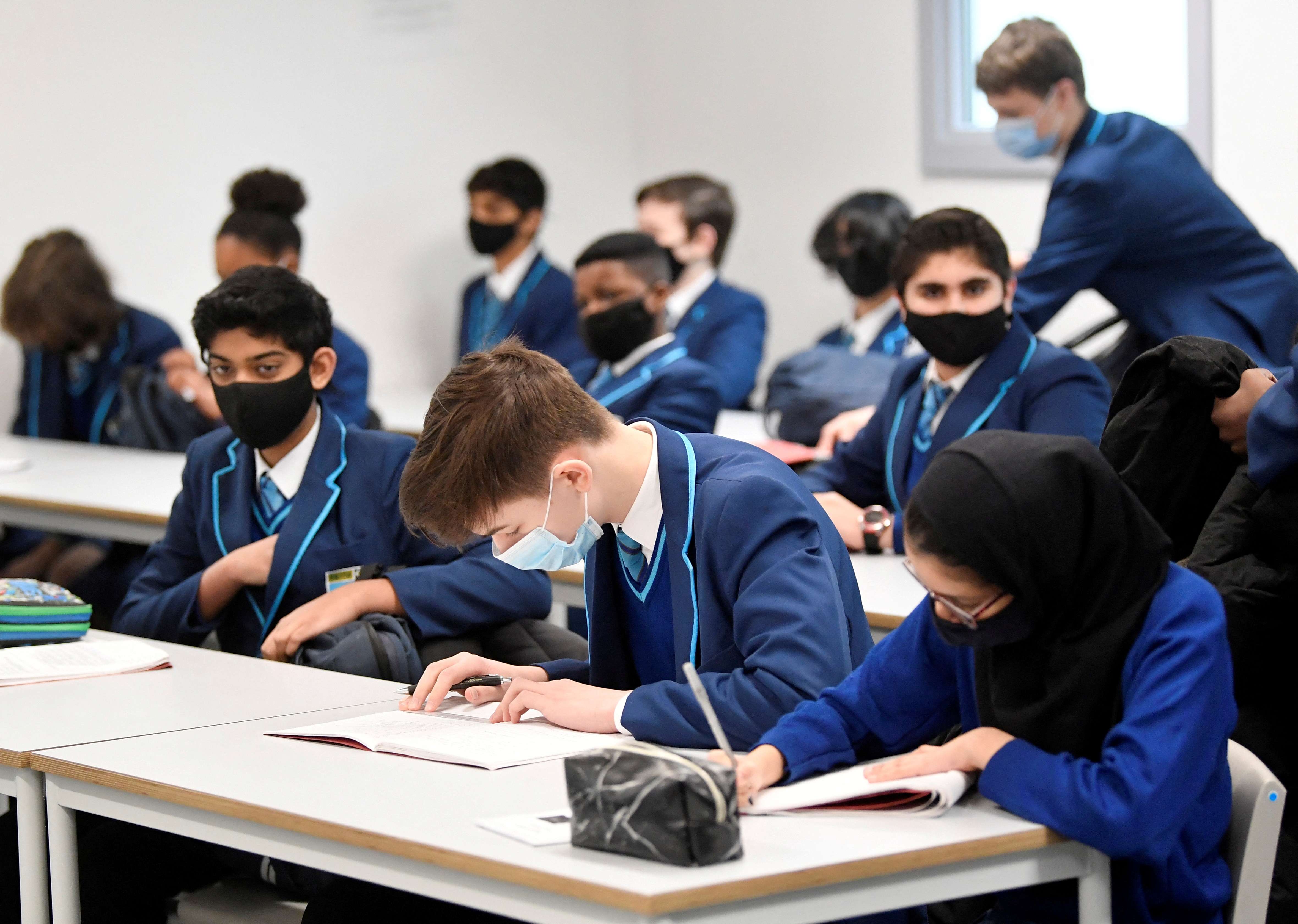 Students wear protective face masks as they study in a classroom in London