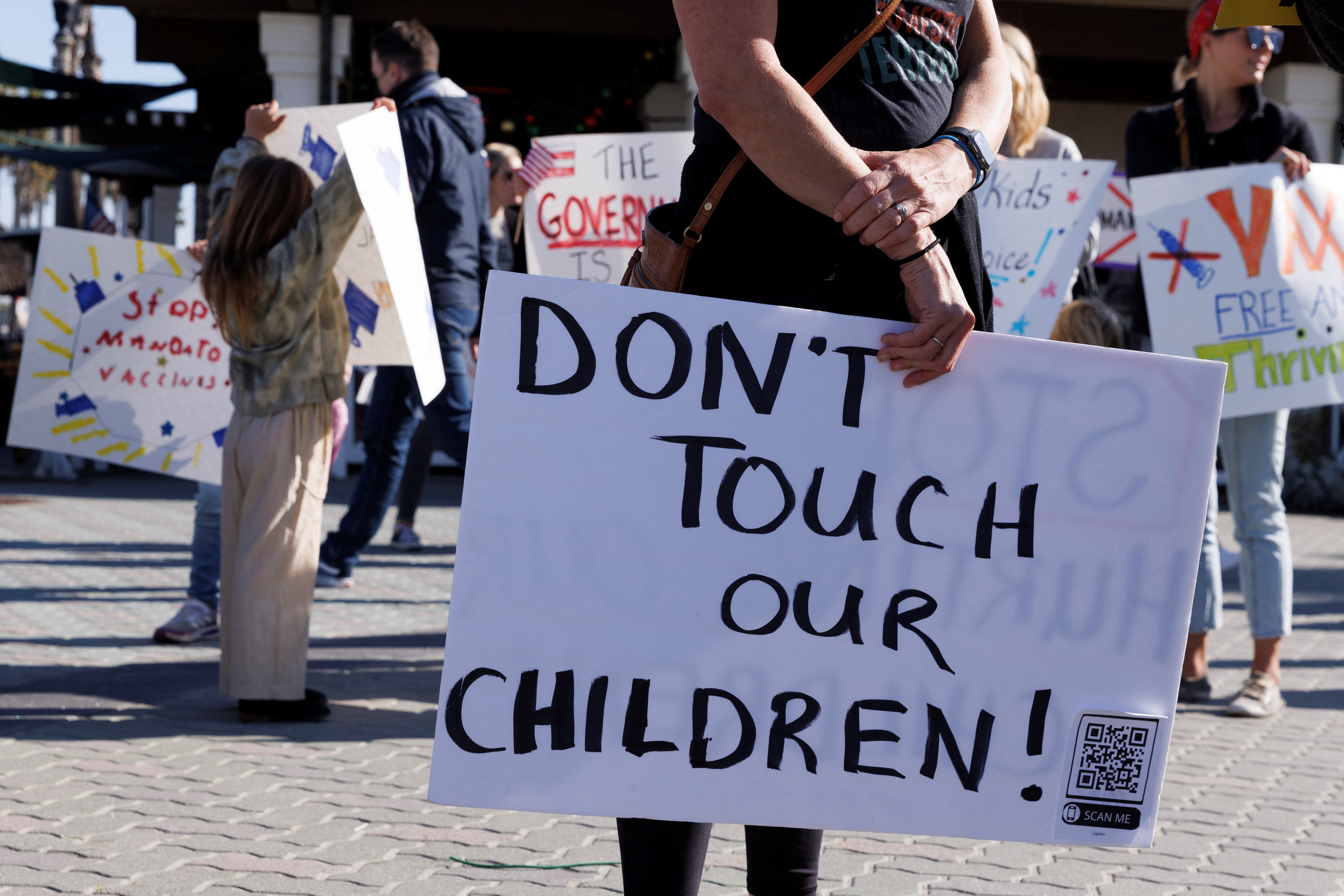 A person displays a sign that reads 'Don't Touch Our Children' as various activist groups hold a rally in California against the vaccination of children.