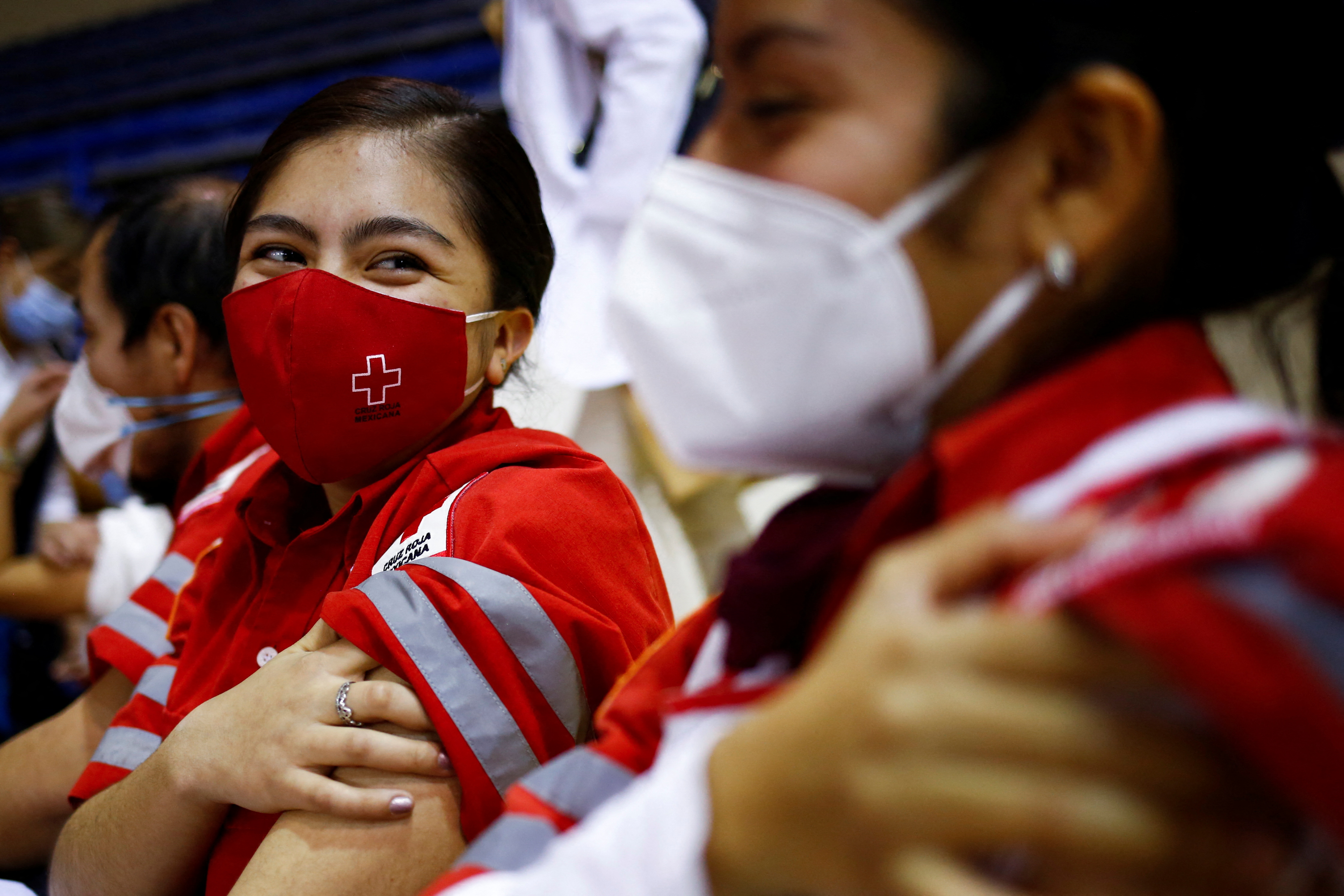 Mexican Red Cross paramedics press on her arm after receiving a booster shot of the AstraZeneca vaccine, in Ciudad Juarez, Mexico