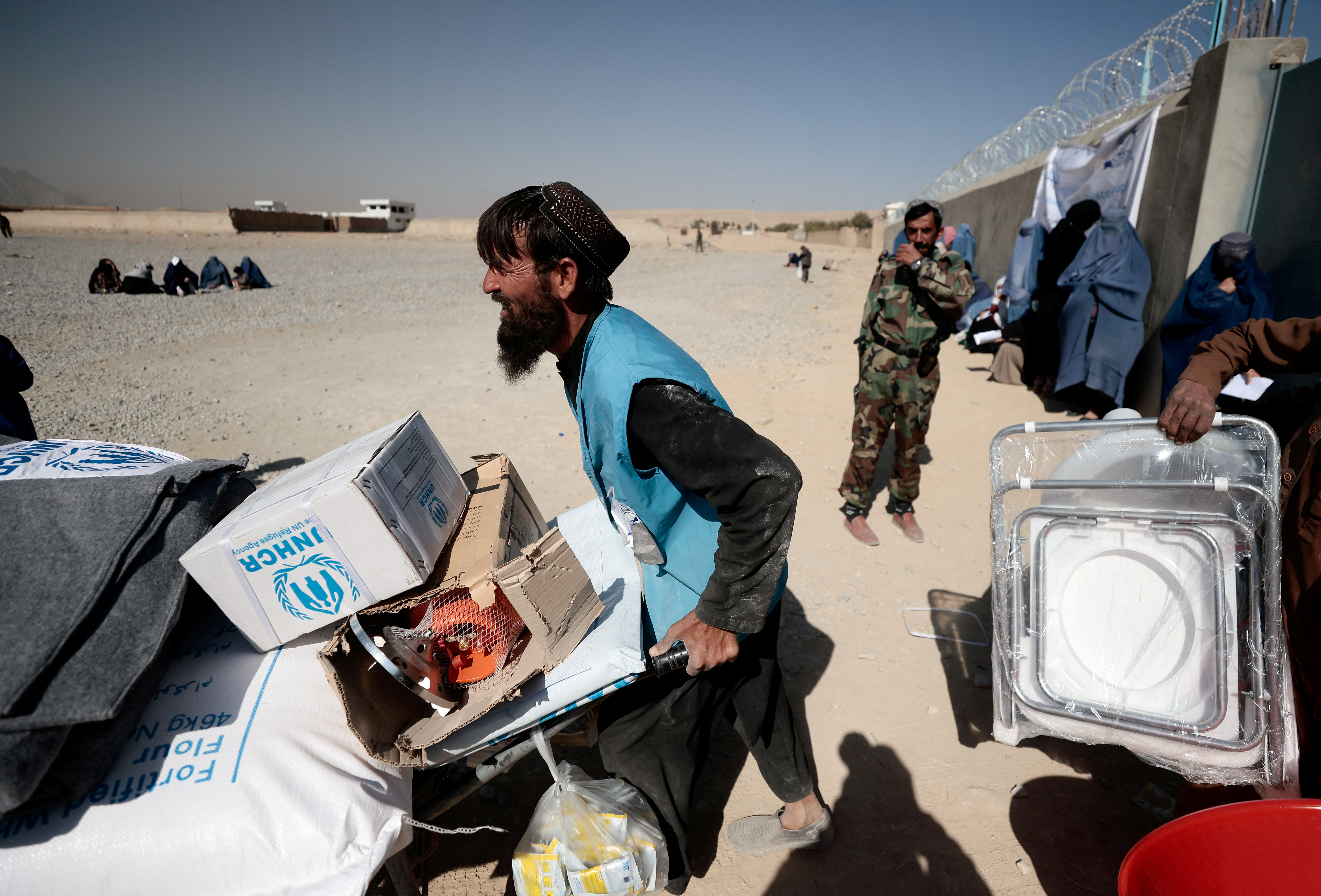 A UNHRC worker pushes a wheelbarrow with aid supplies outside Kabul