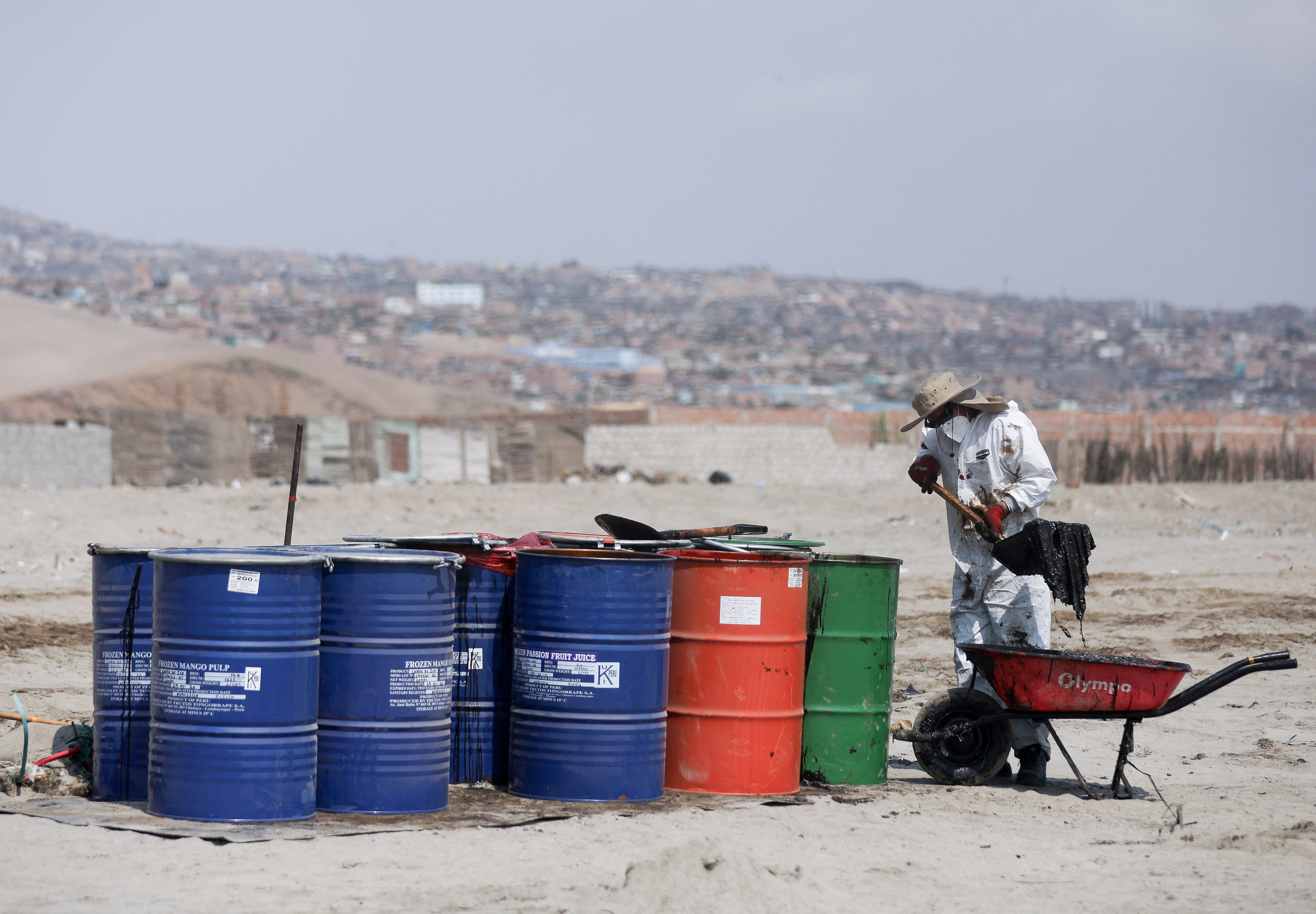 Workers clean up an oil spill caused by abnormal waves in Ventanilla, Peru