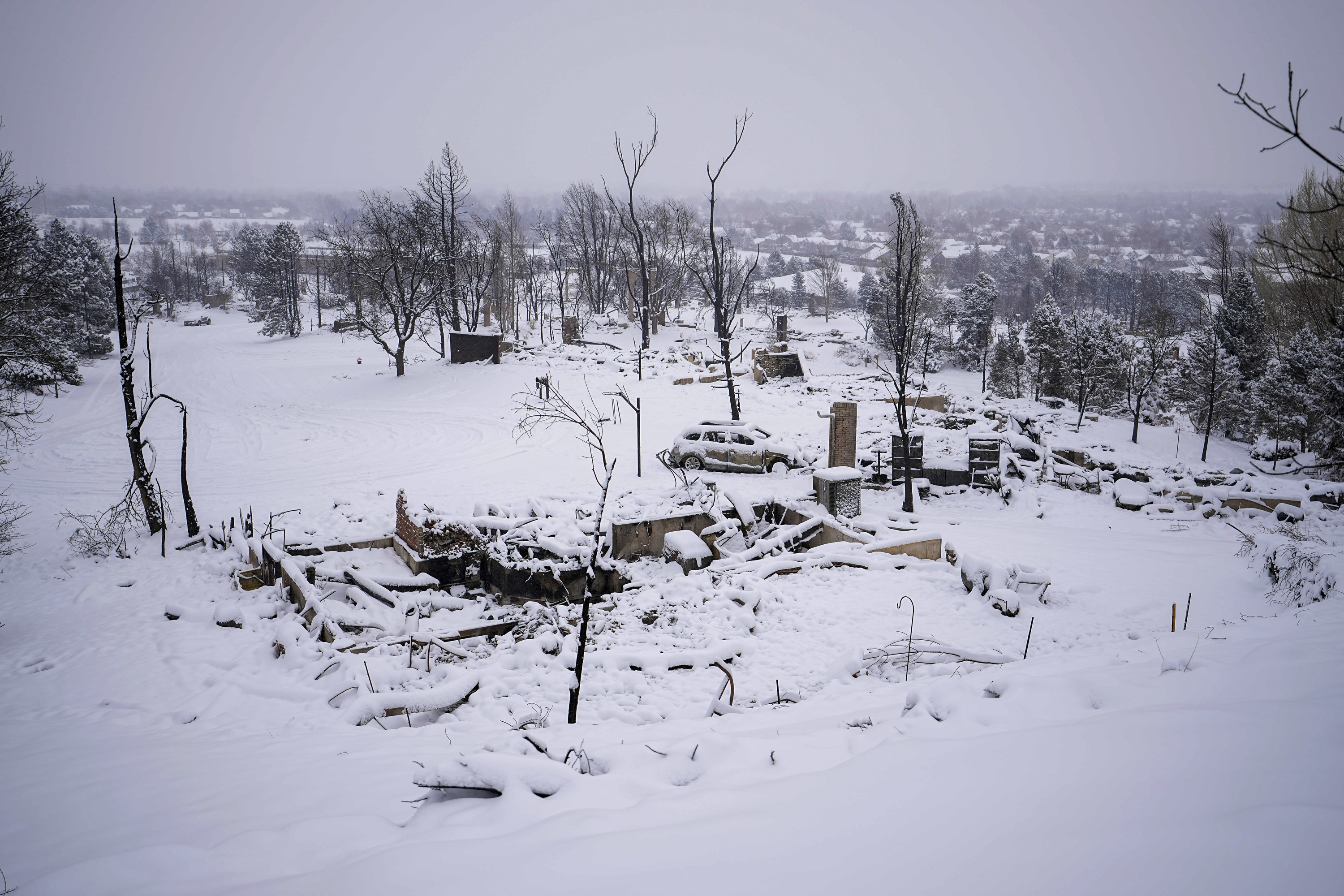 Snow covers the burned remains of homes in Louisville Colorado