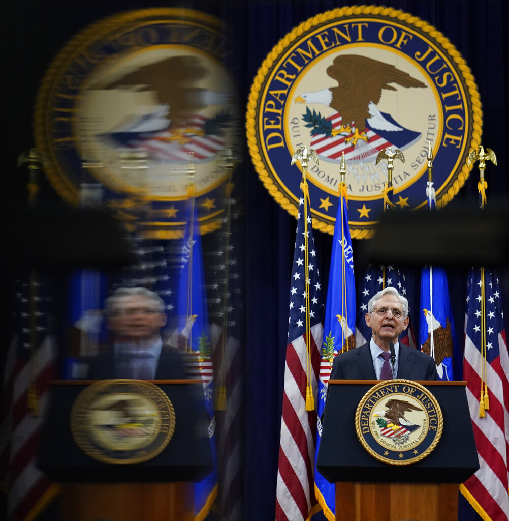 Attorney General Merrick Garland is reflected in a technician's monitor as he speaks at the Department of Justice.