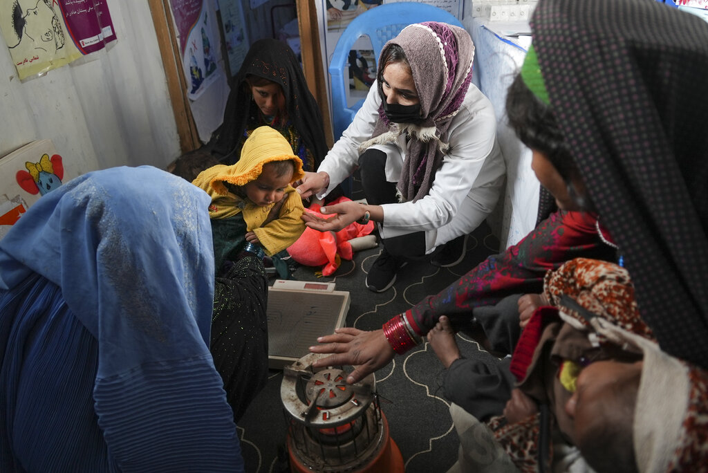 A nurse checks the weight of a child in a makeshift clinic organized by World Vision at a settlement near Herat, Afghanistan.