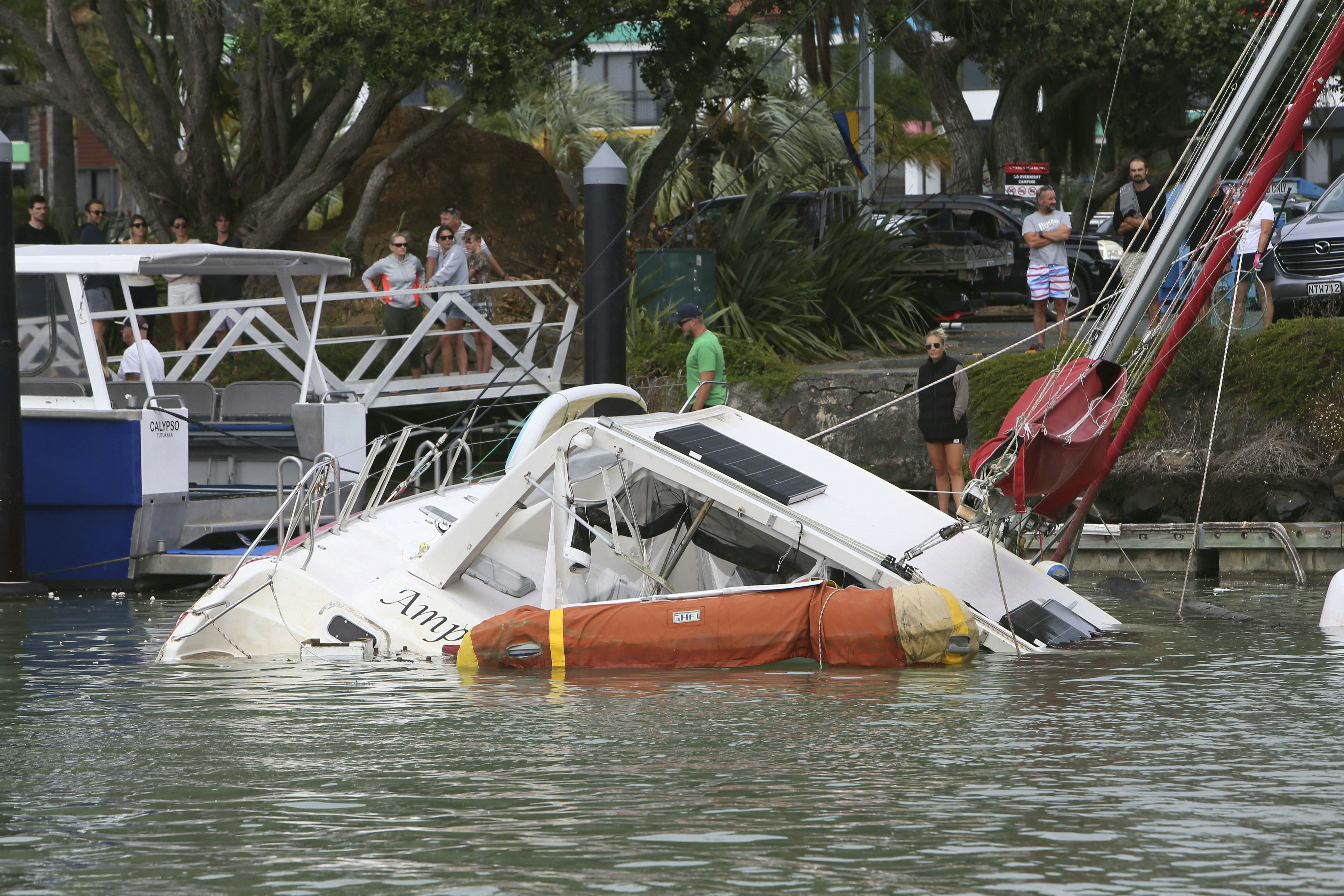 People look at a damaged boat in a marina at Tutukaka, New Zealand