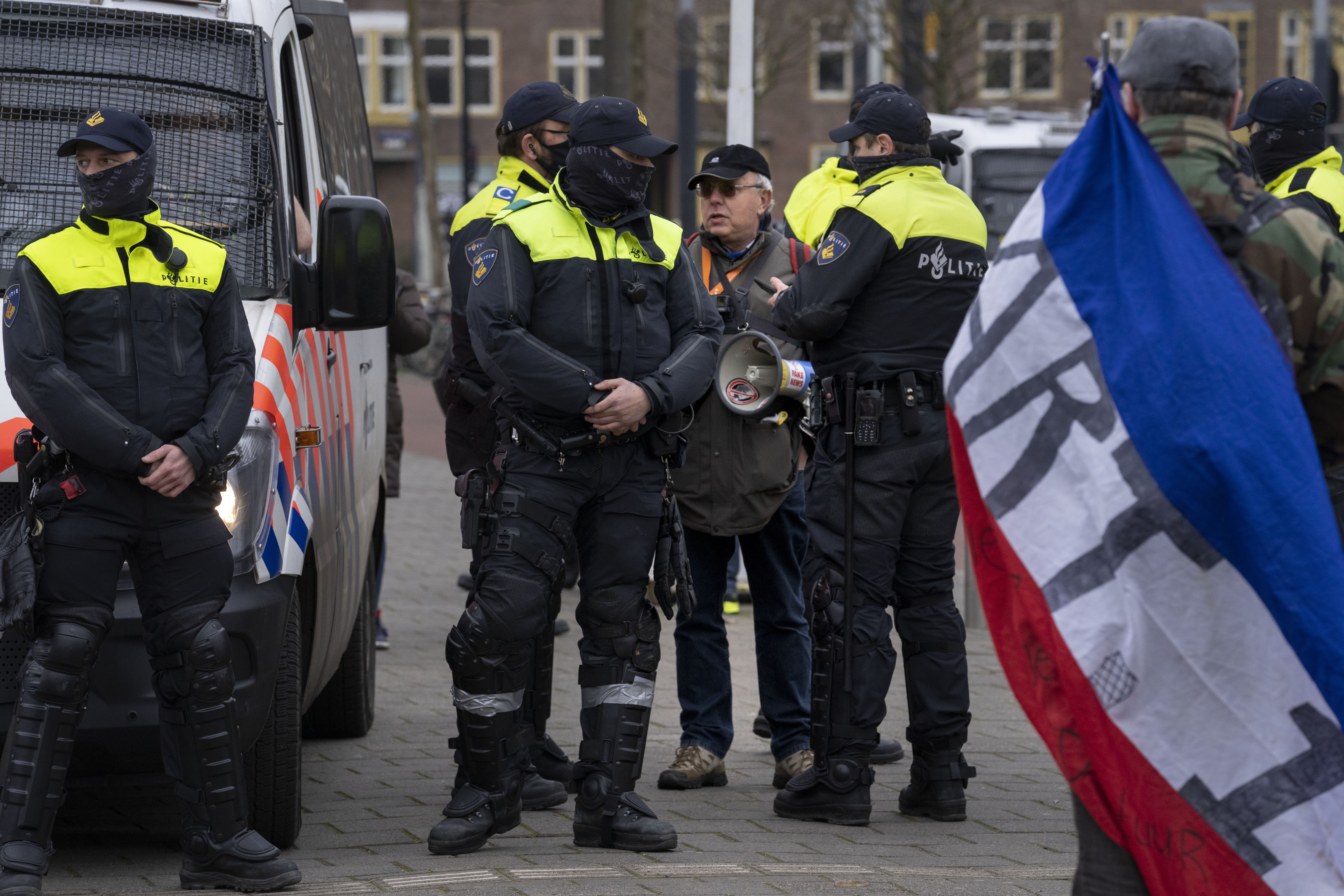 Dutch police arrest a man with a bullhorn as thousands of people gathered to protest against the Dutch government's coronavirus lockdown measures 