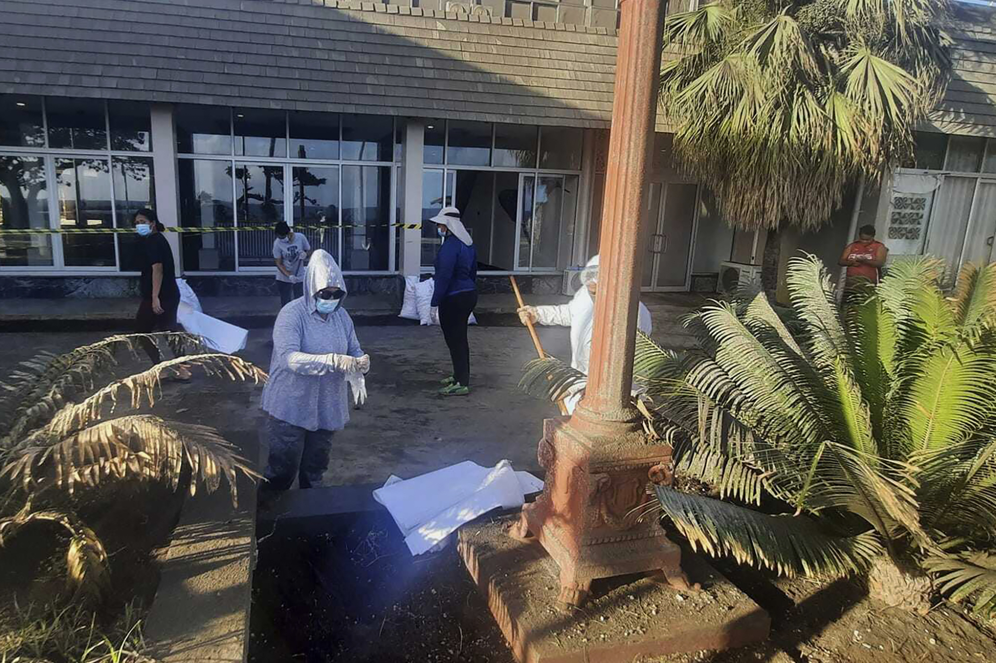 People clear ash off a damaged area in Nuku'alofa, Tonga