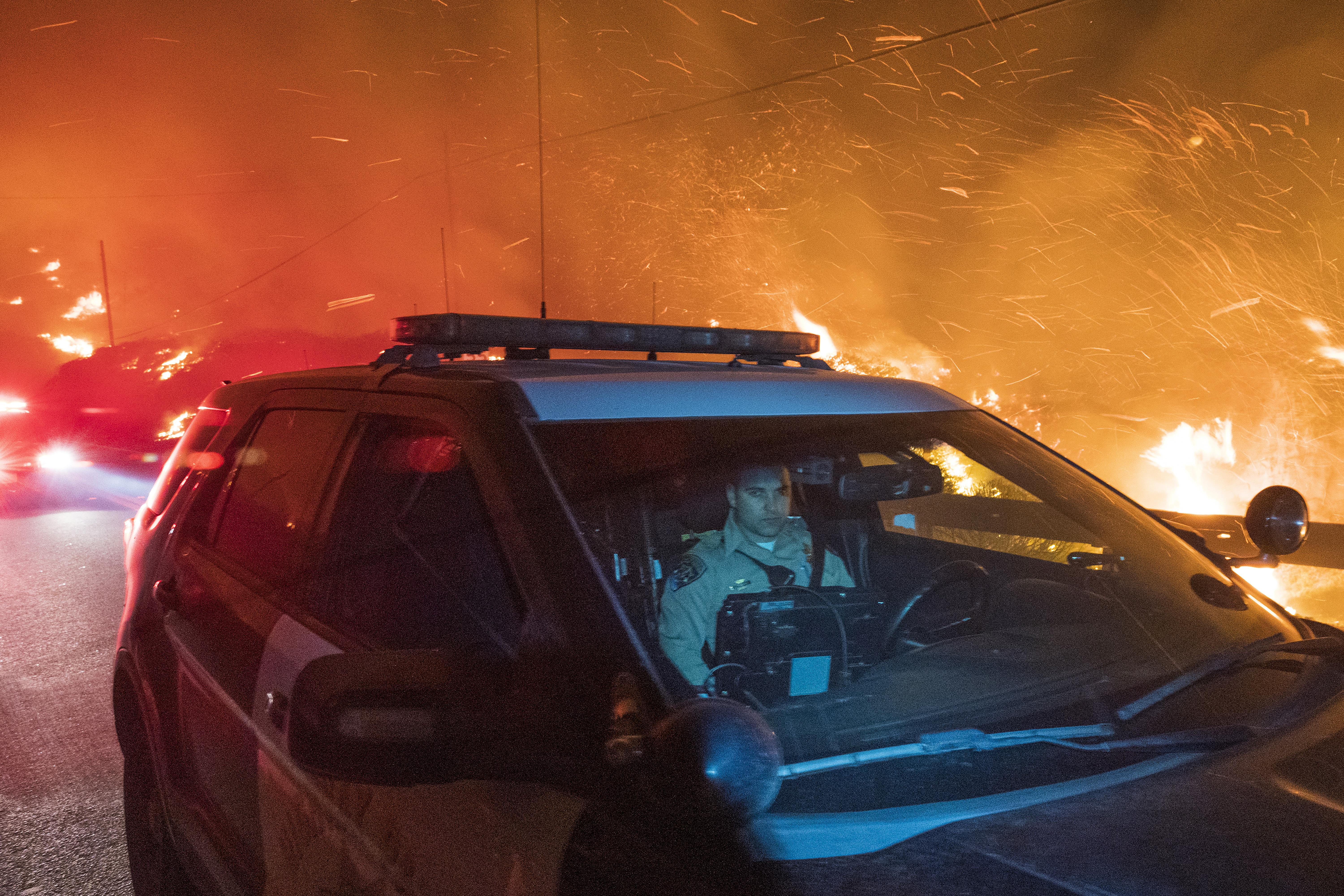 A California Highway Patrol officer drives south on Highway 1 as the Colorado Fire burns near Big Sur