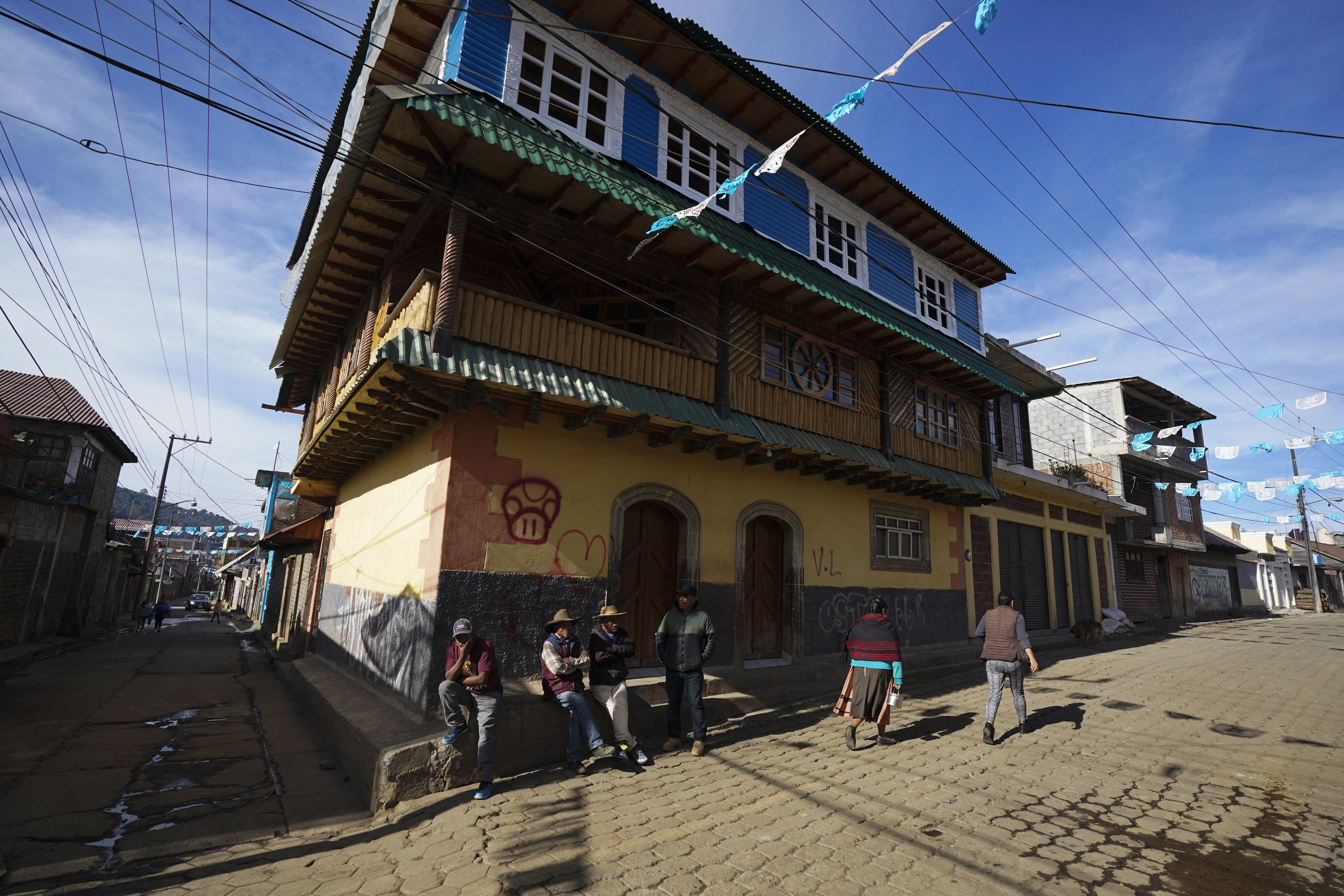 Residents gather on a street corner next to a home built with money earned in the United States, in the Puerpecha Indigenous community