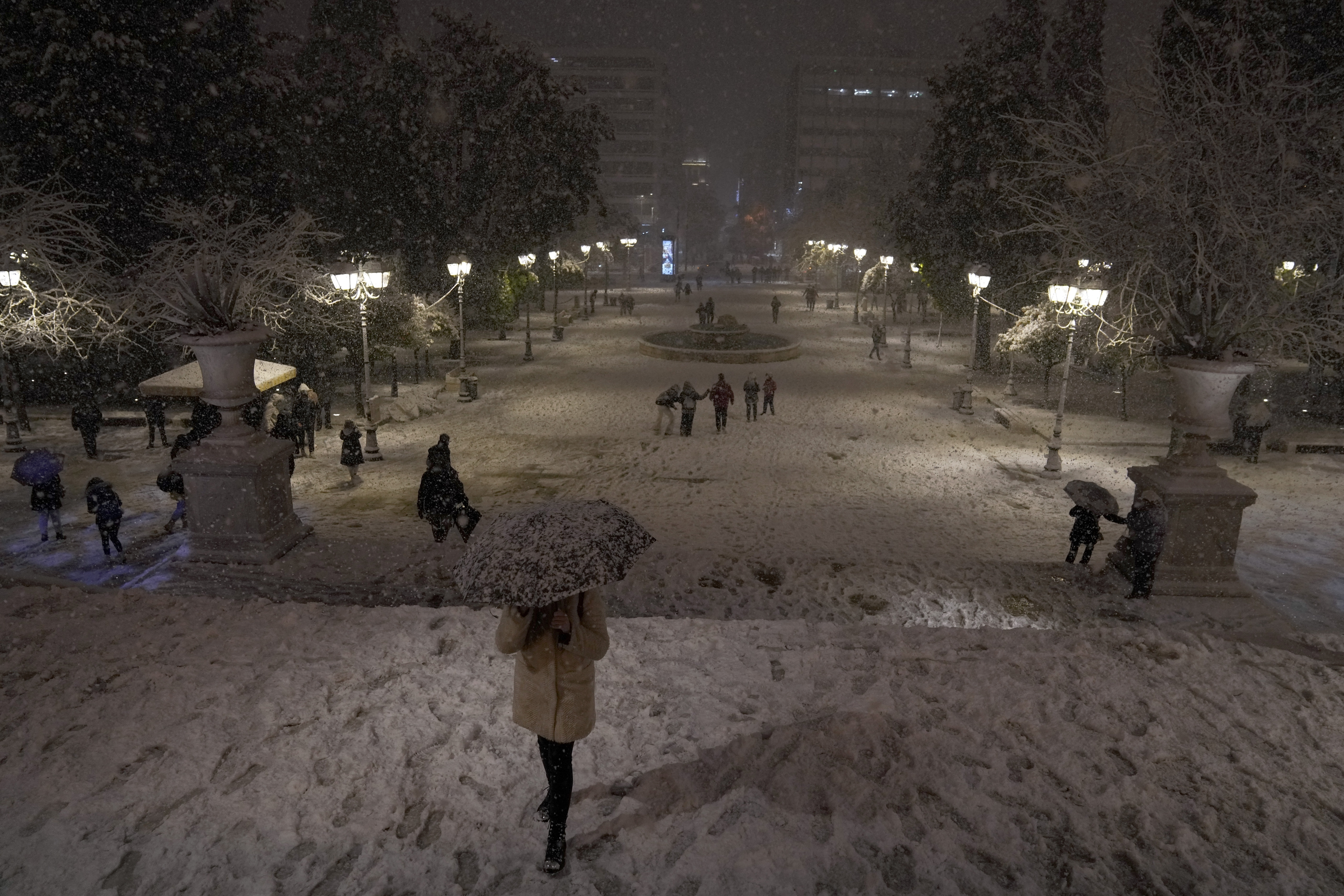 People walk on the snow-covered Syntagma square during snowstorm in Athens