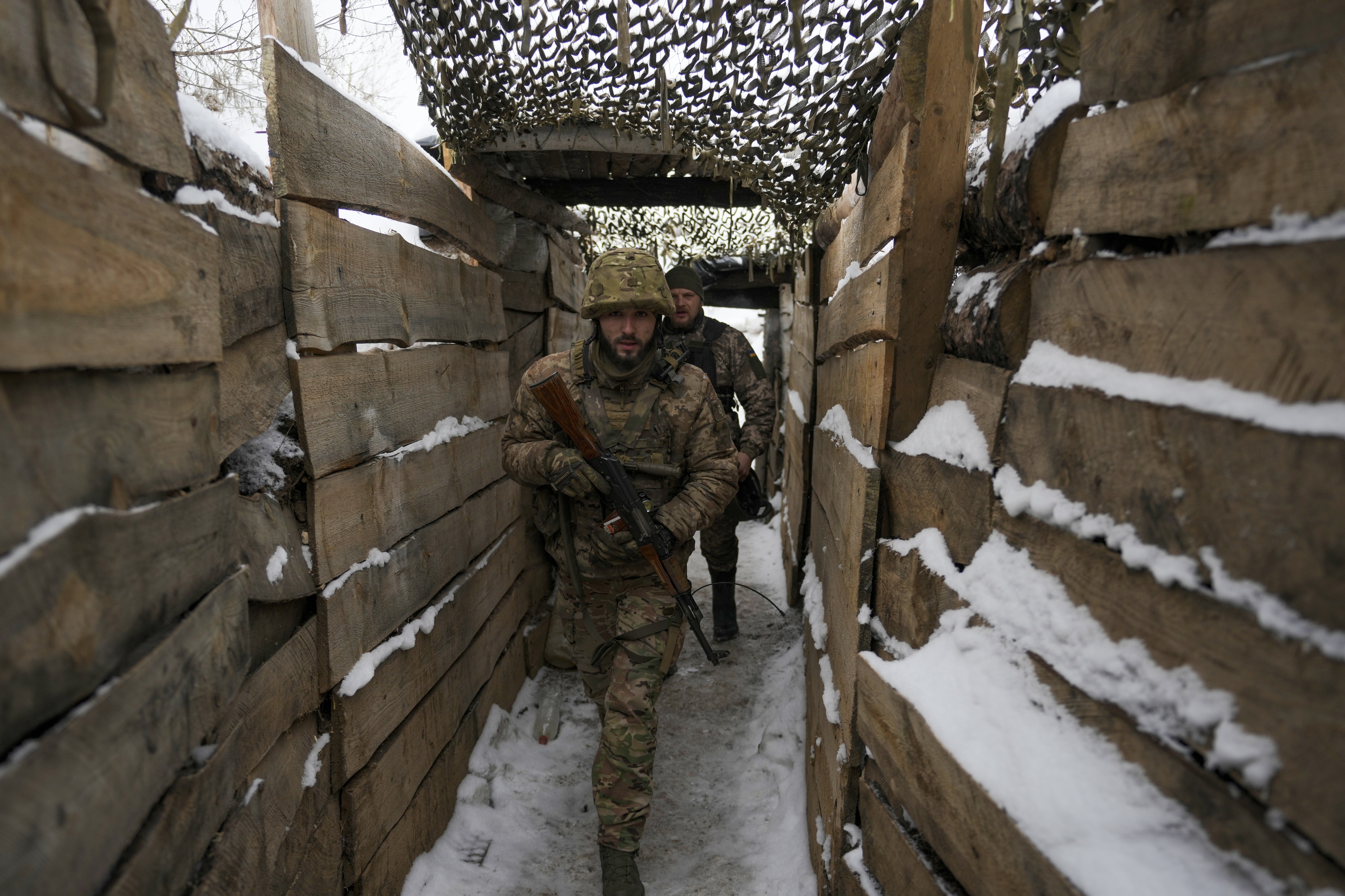 Ukrainian servicemen walk in a trench on the front line in the Luhansk region, eastern Ukraine, Friday, Jan. 28, 2022.