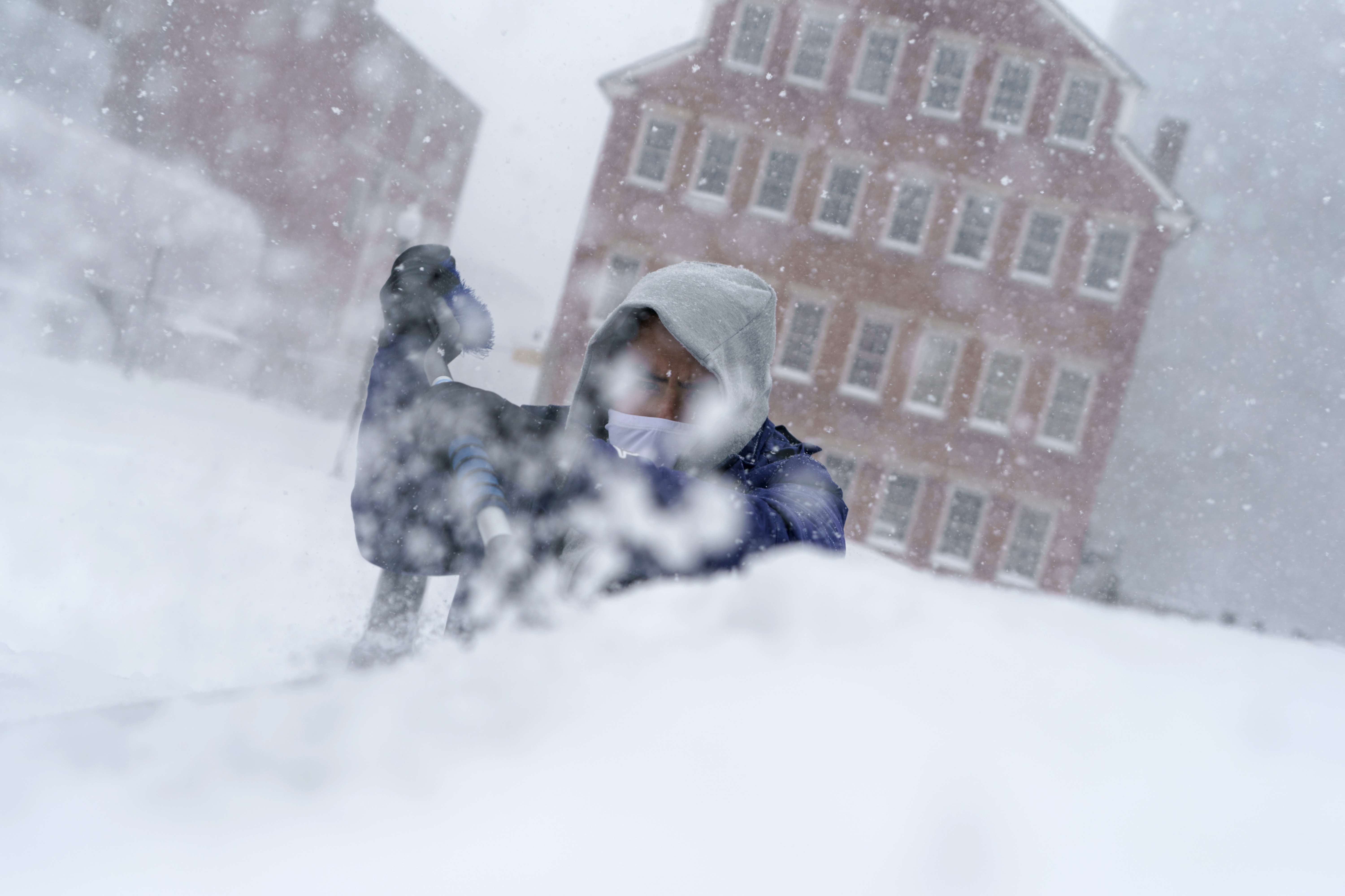 Xavier Martinez scrapes snow off his windshield during a storm in Providence, R.I