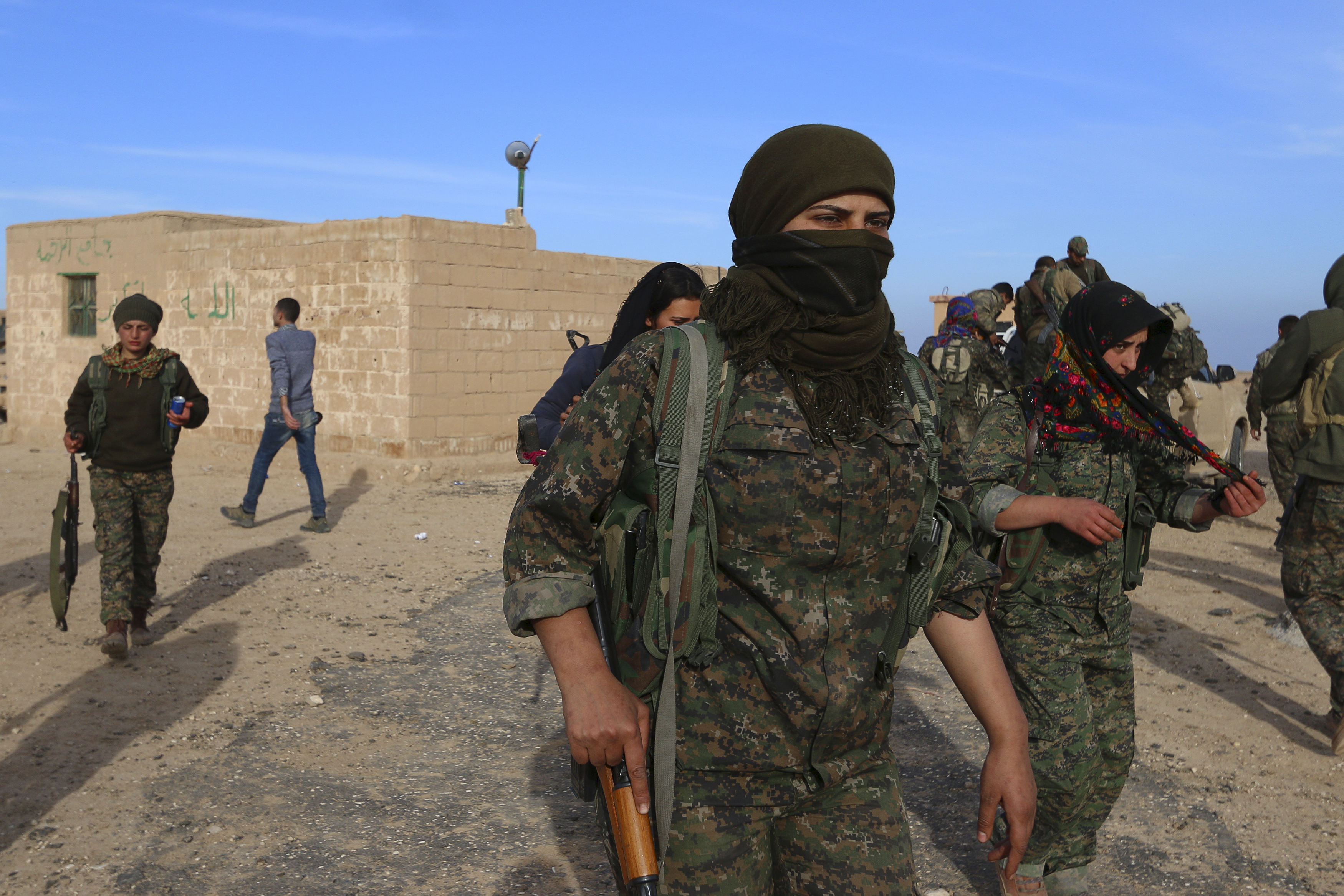 Fighters from the Democratic Forces of Syria carry their weapons in Ghazila village