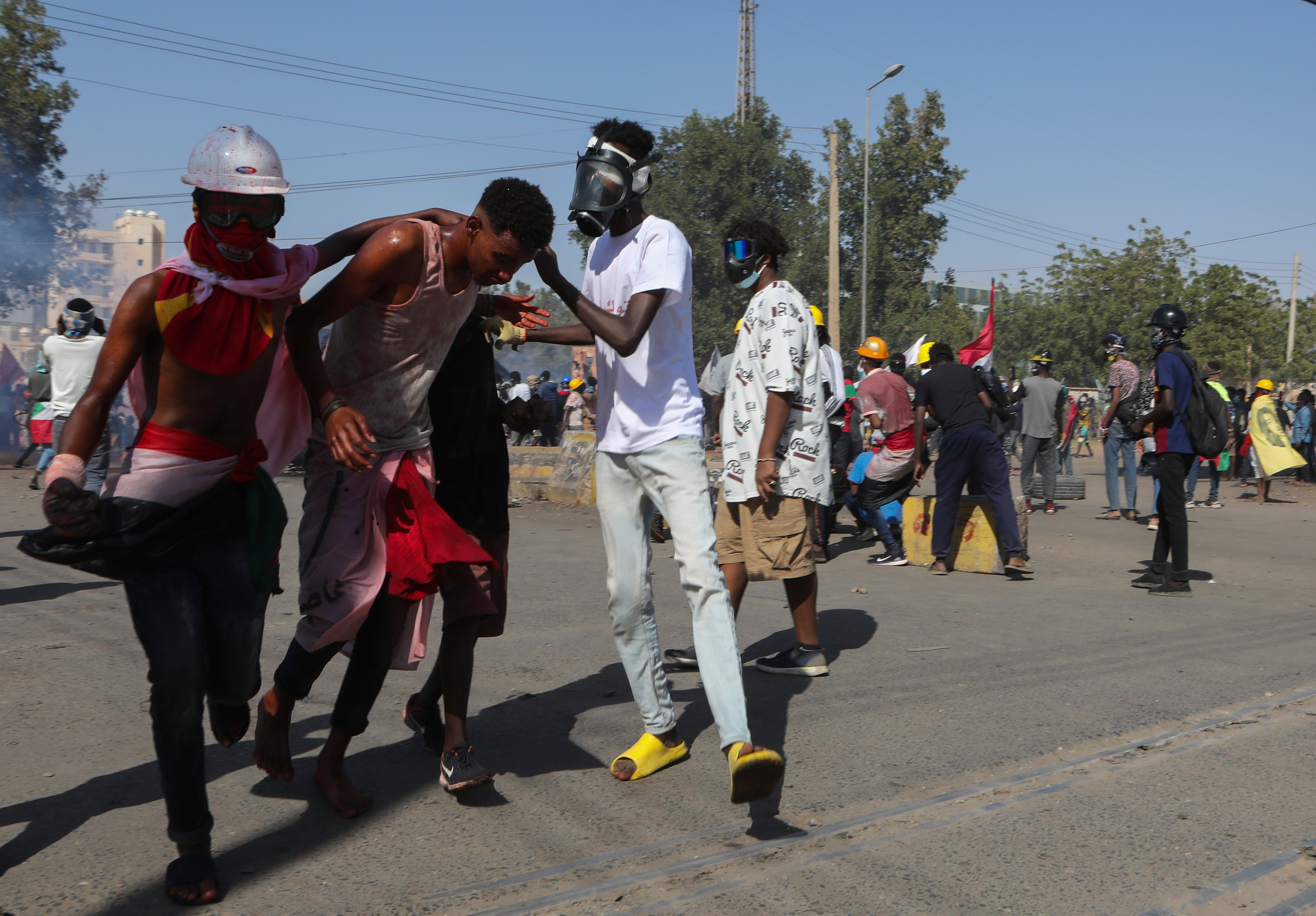 Sudanese people assist a fellow protester during clashes with security forces at a protest against military coup, in Khartoum, Sudan, 30 January 2022.