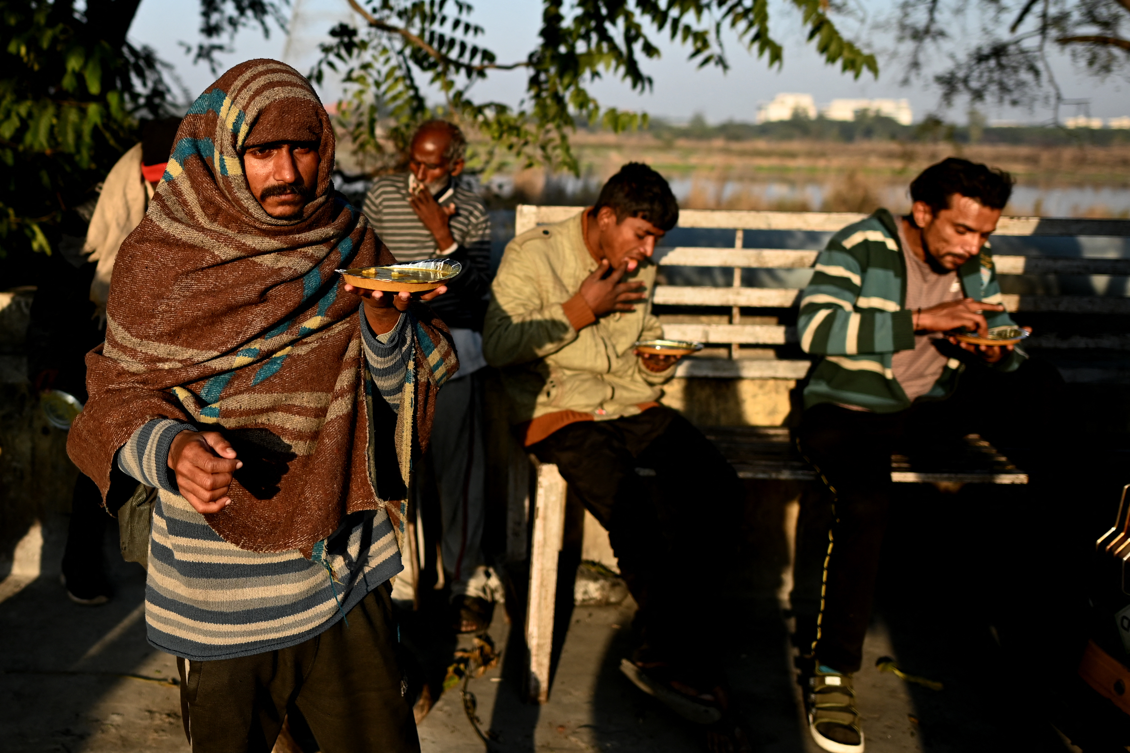 In this picture taken on January 29, 2022, shows homeless people eating their meals provided to them near the government-run shelter in New Delhi.