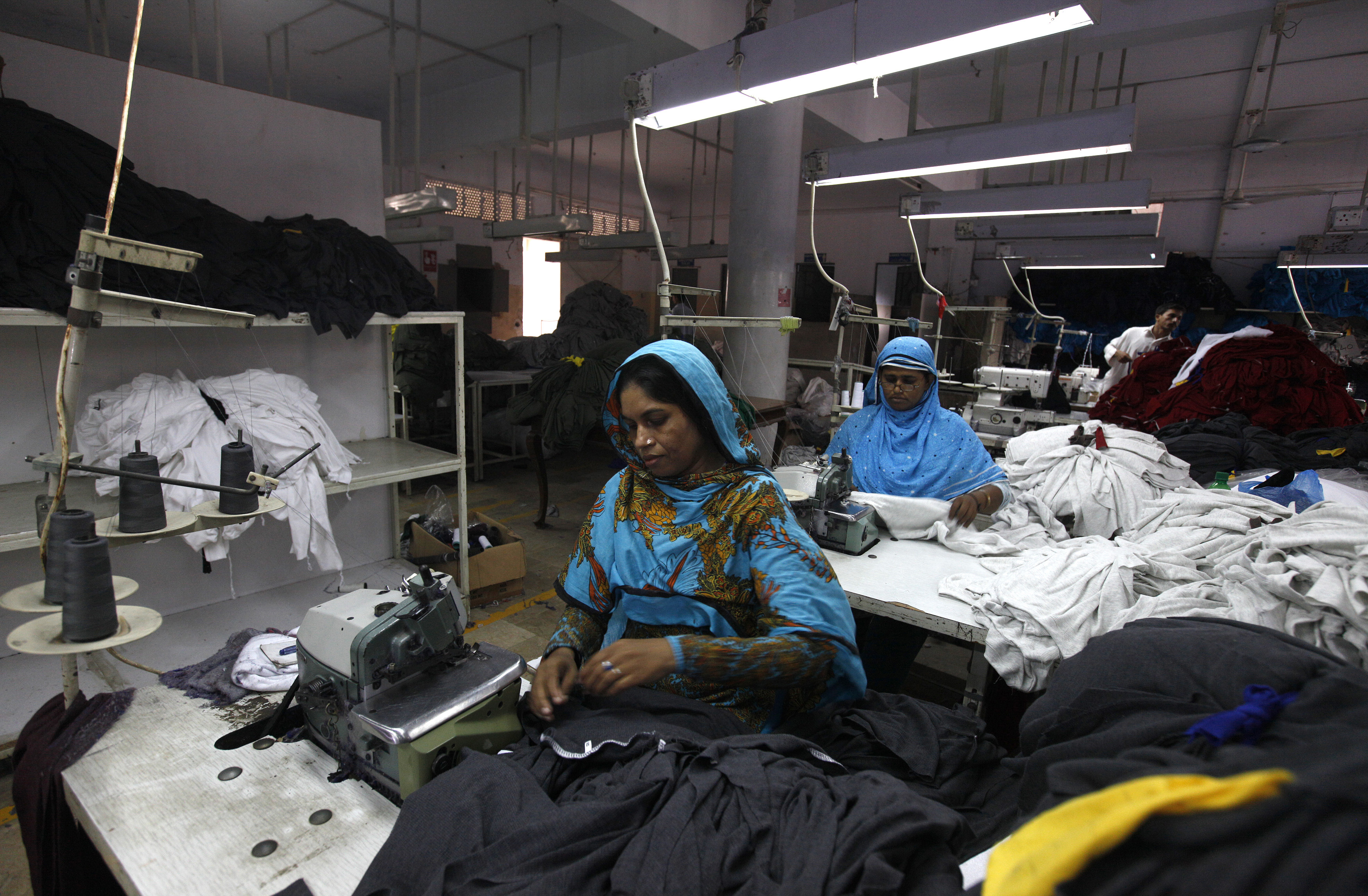 Women workers sew fabrics at a garment factory in Karachi, Pakistan