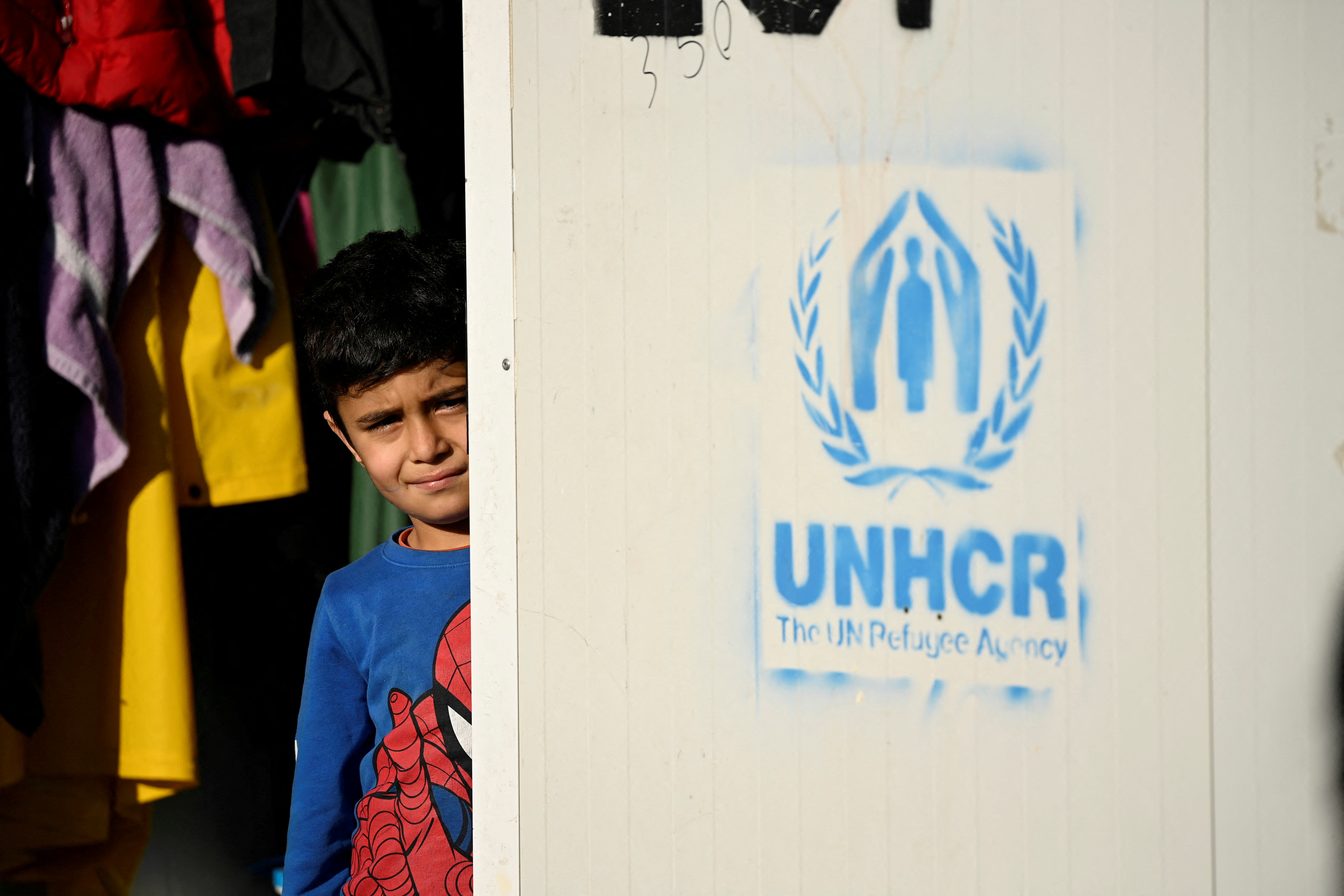 A child looks on next to the UNHCR logo