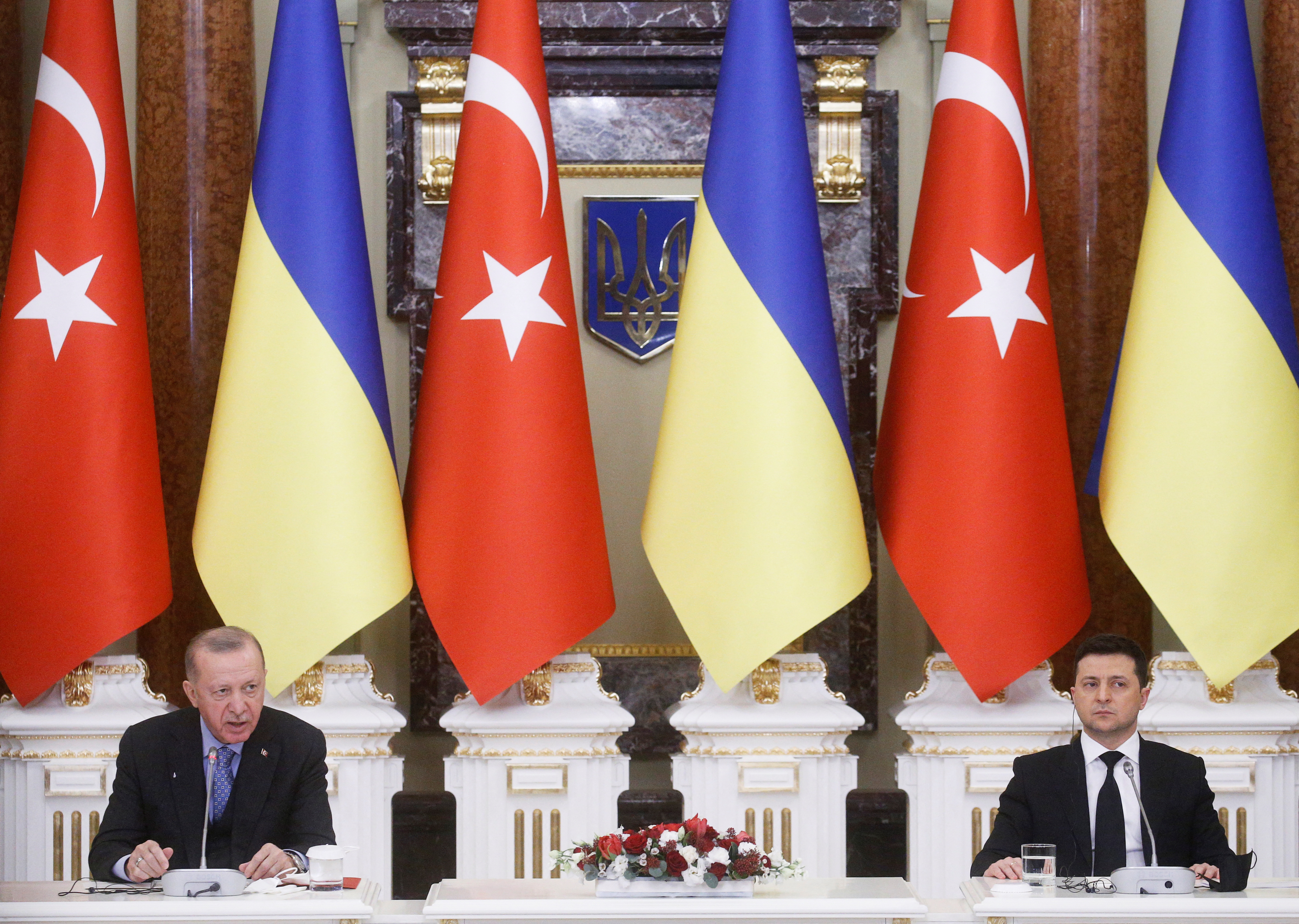 Turkish President Tayyip Erdogan and Ukrainian President Volodymyr Zelenskiy sit at a desk and attend a joint news conference in Kyiv, Ukraine with large national flags of Turkey and Ukraine set up in the background