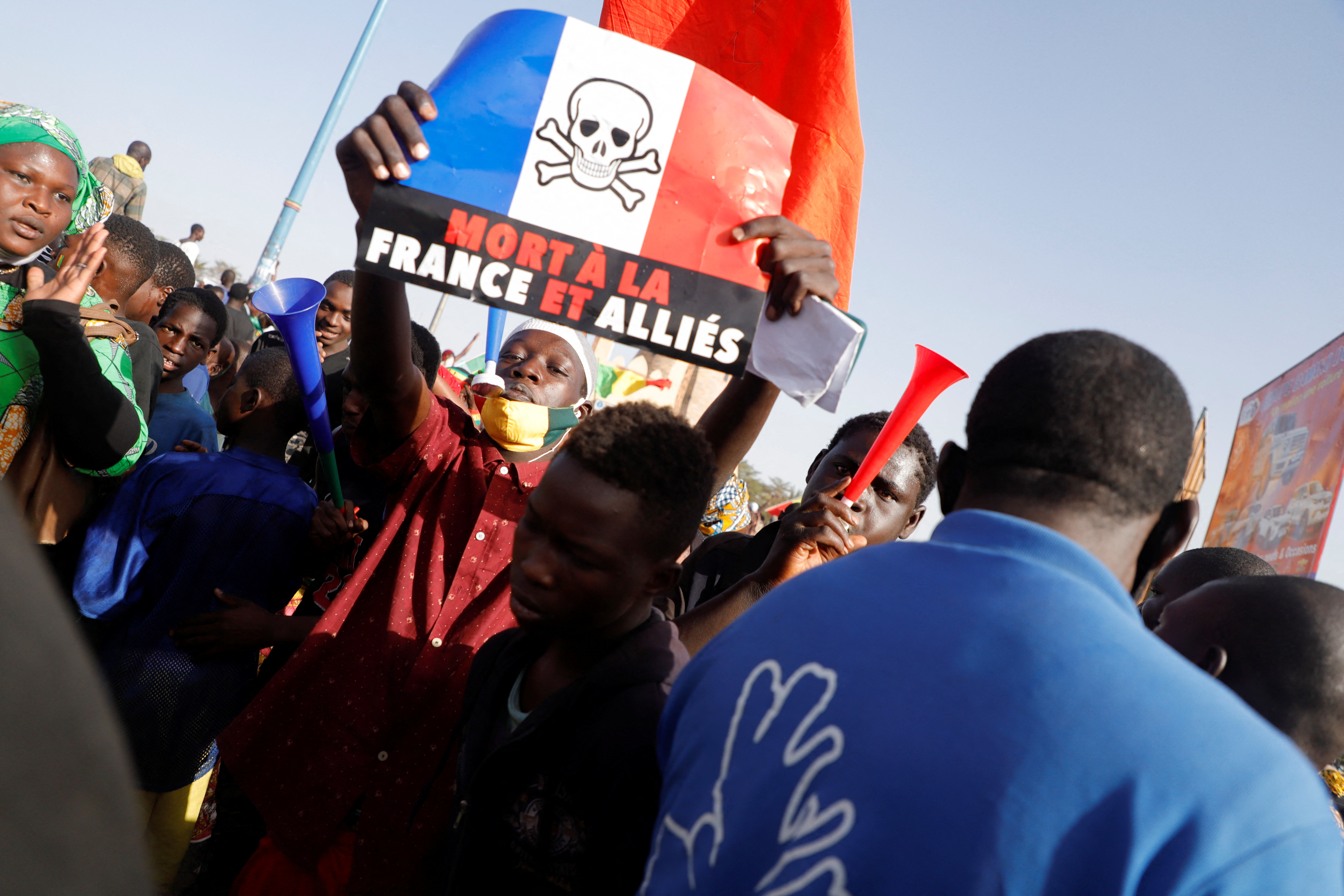 Protesters hold a placard of a French flag with a skull and corssbones drawn on top at an anti-French rally in Mali