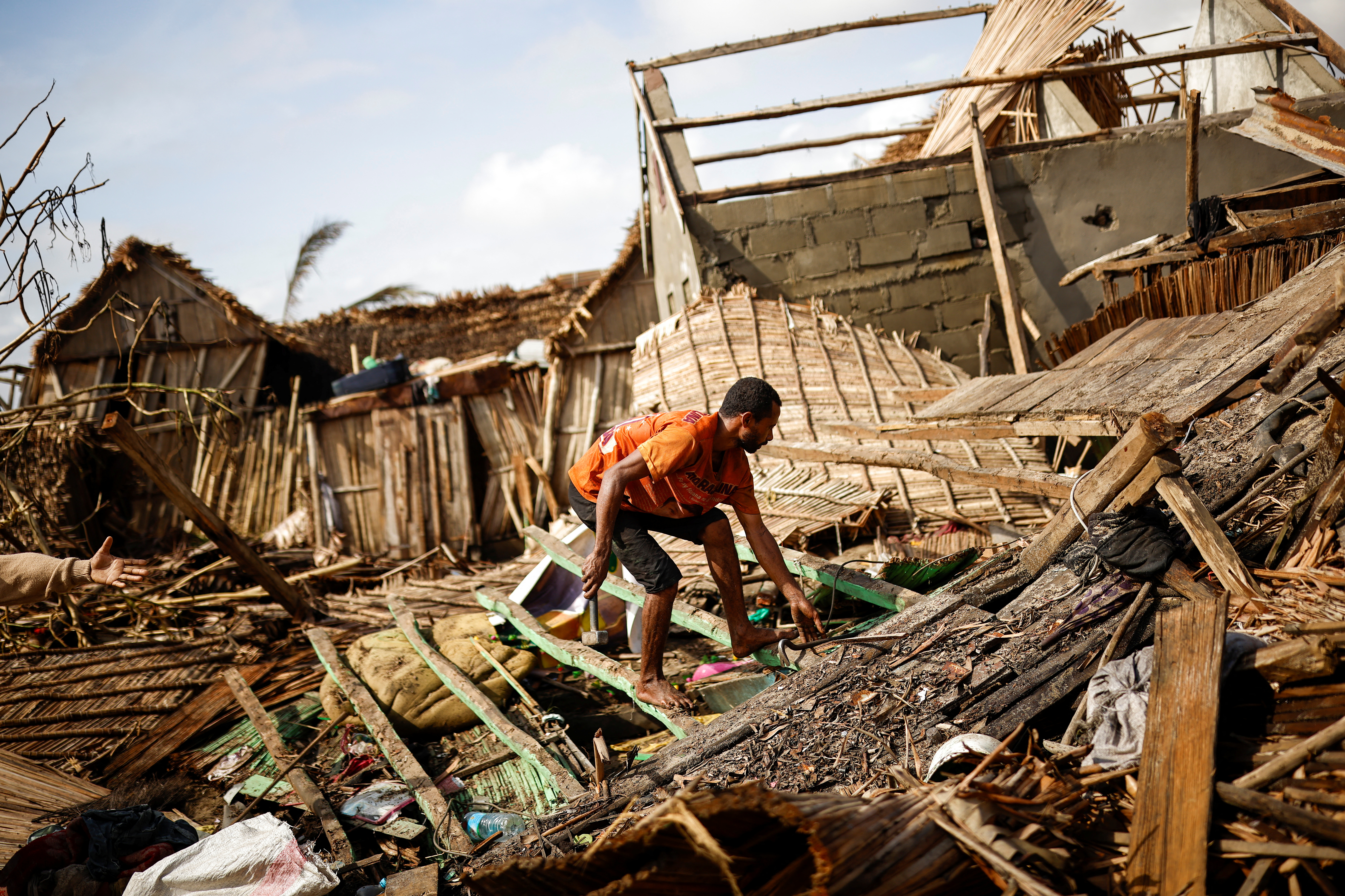 A man works on the destroyed house of Philibert Jean Claude Razananoro, in the aftermath of Cyclone Batsirai