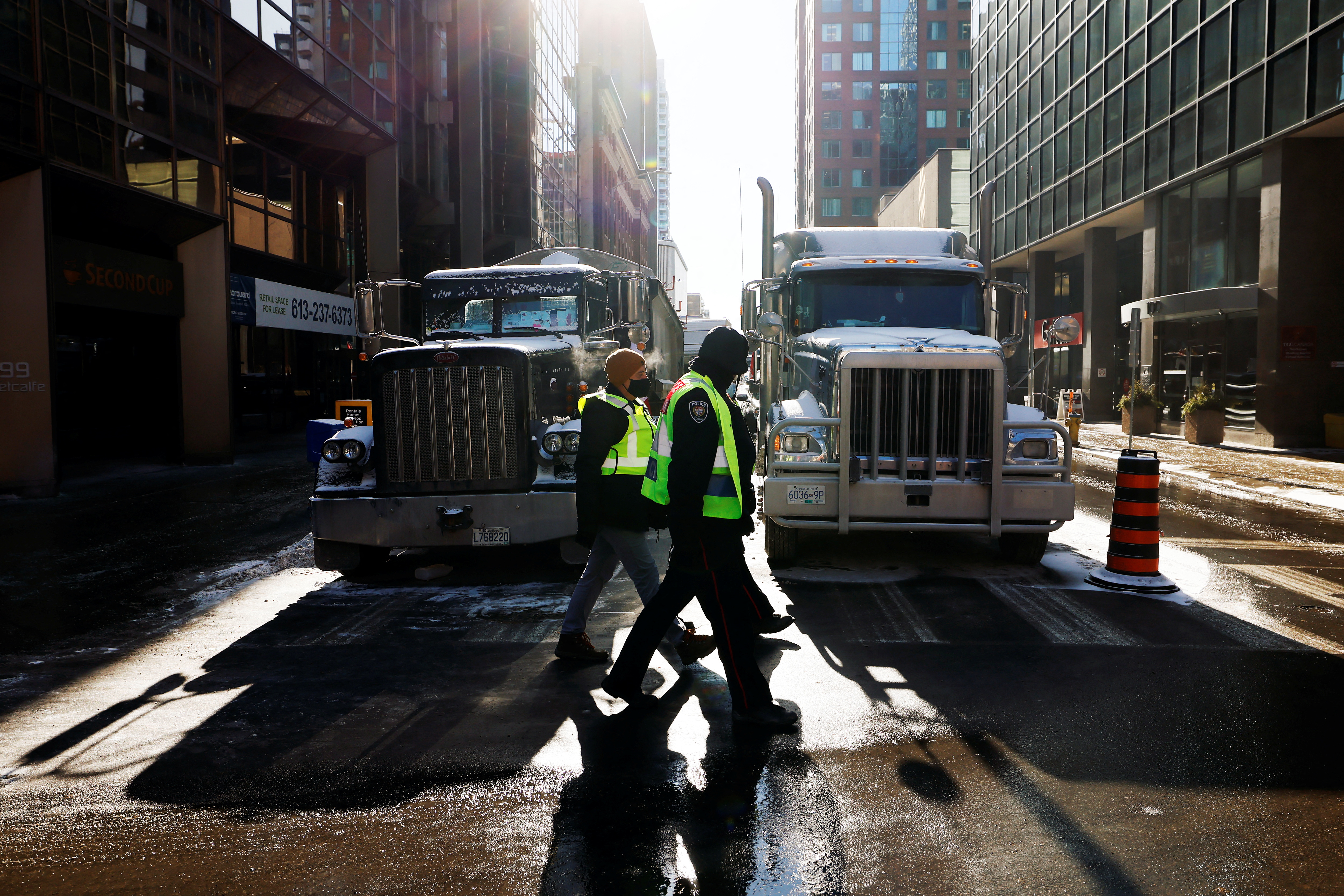 Police officers walk by trucks in downtown Ottawa