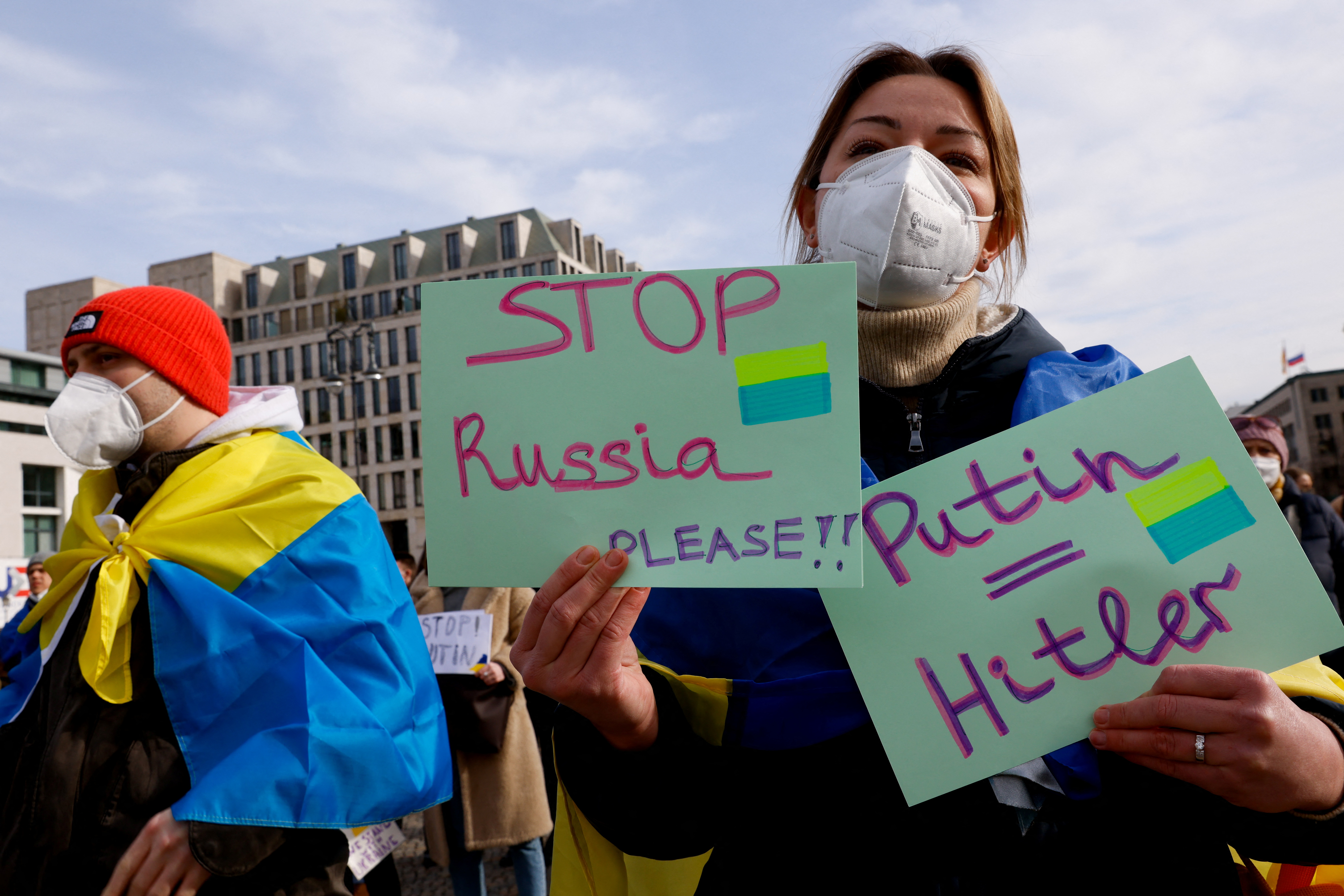 A person holds signs during a protest at Brandenburg Gate, Berlin
