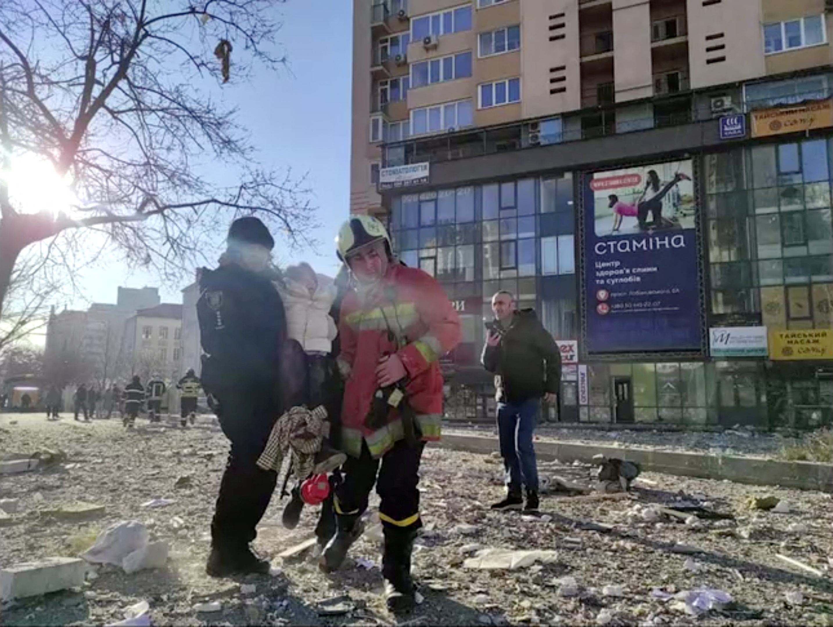 service workers carrying a person at the site of a damaged multi-storey residential building
