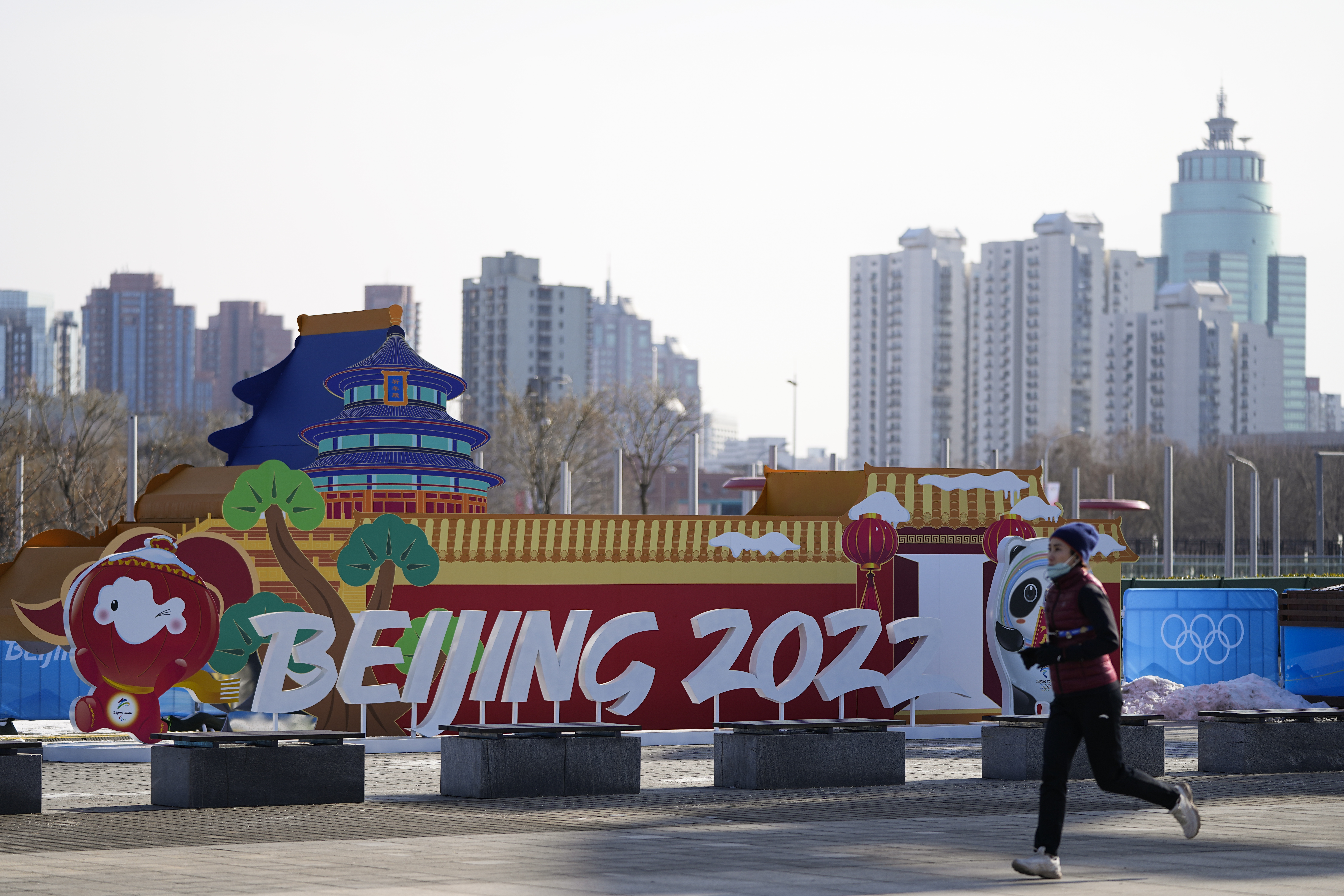 A woman jogs past an installation near the Beijing Olympic Park at the 2022 Winter Olympics, Tuesday, Jan. 25, 2022, in Beijing. (AP Photo/Jae C. Hong)
