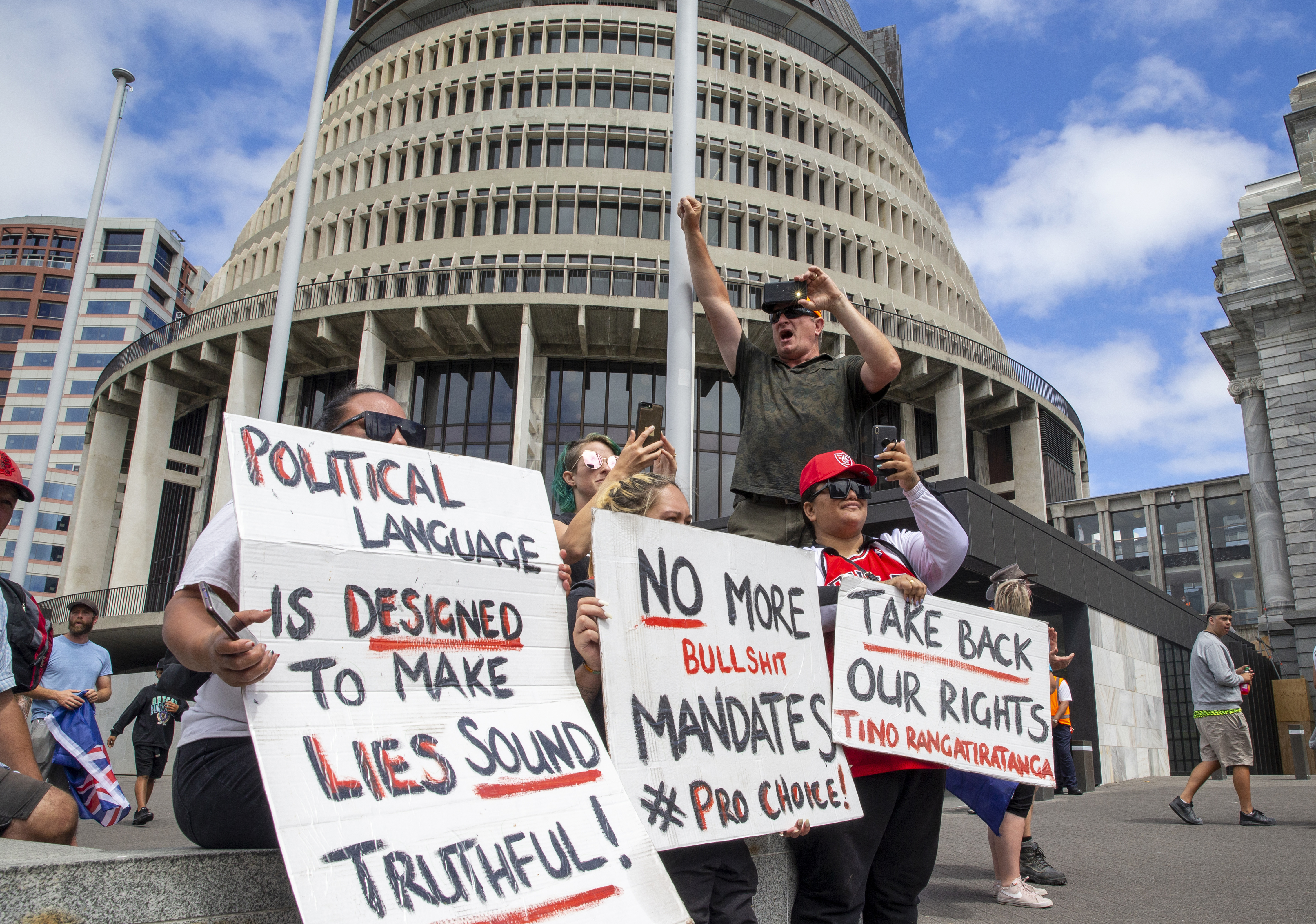 A small group of protesters outside the Beehive hold placards against vaccine requirements and calling for 'rights'