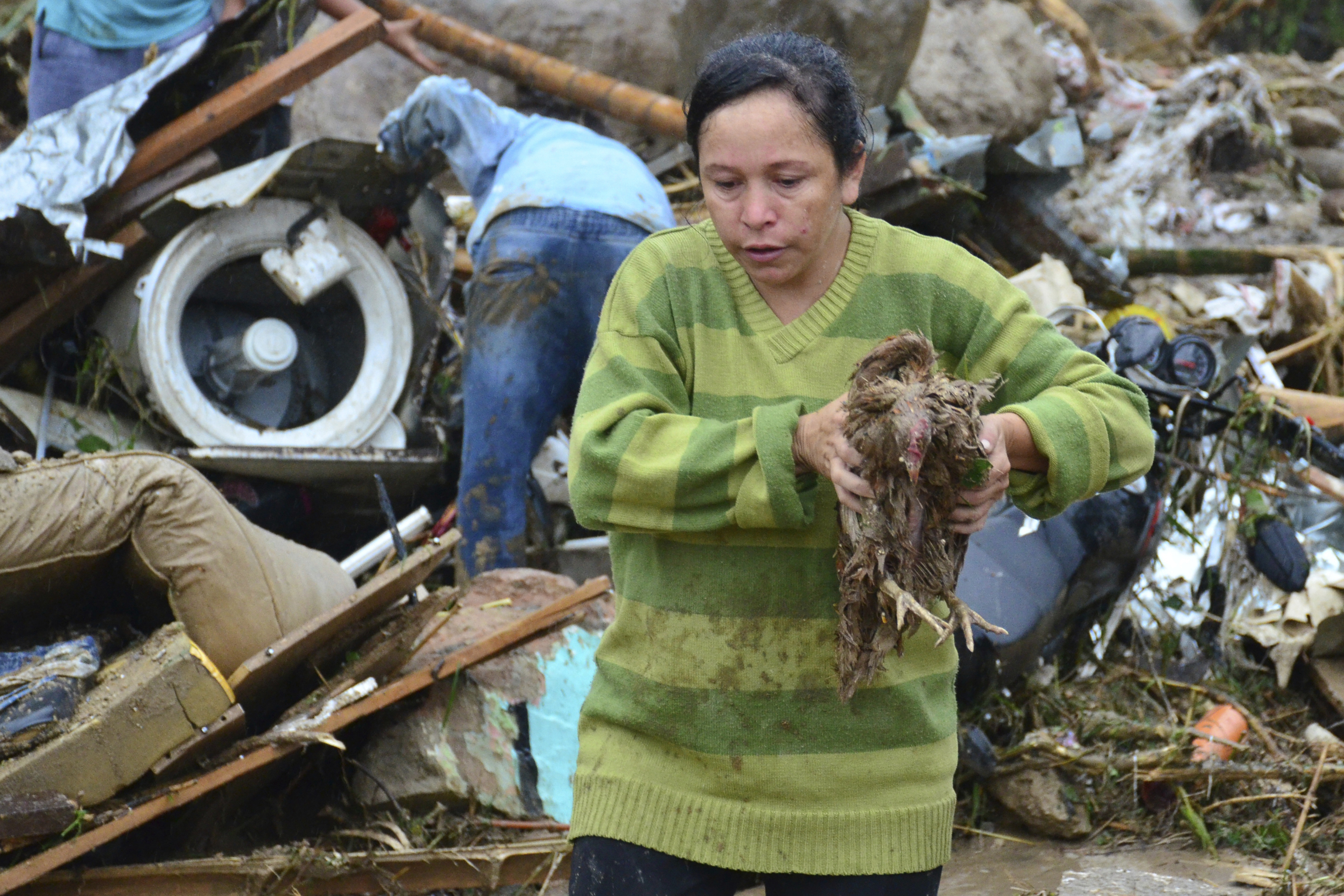 A woman carries a live chicken from the debris