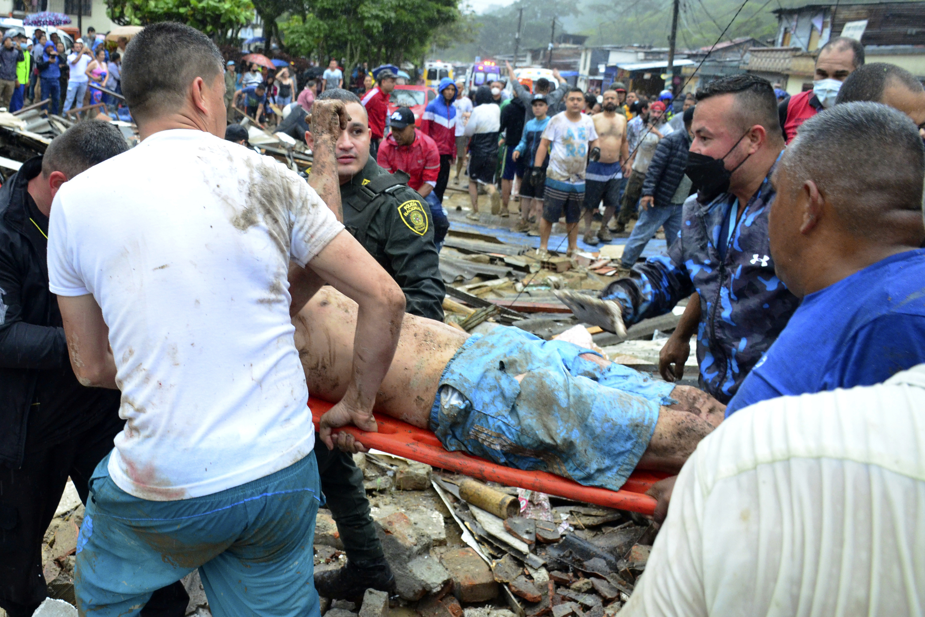 Police and rescue workers evacuate a survivor from the site of a rain-weakened hillside that collapsed over homes in Pereira
