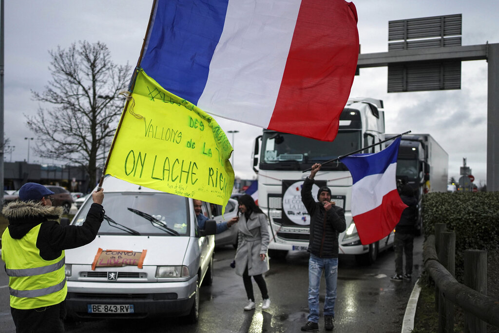 A protester waves a French flag at a convoy made of vehicles, from trucks to motorcycles and camper vans, in Lyon.