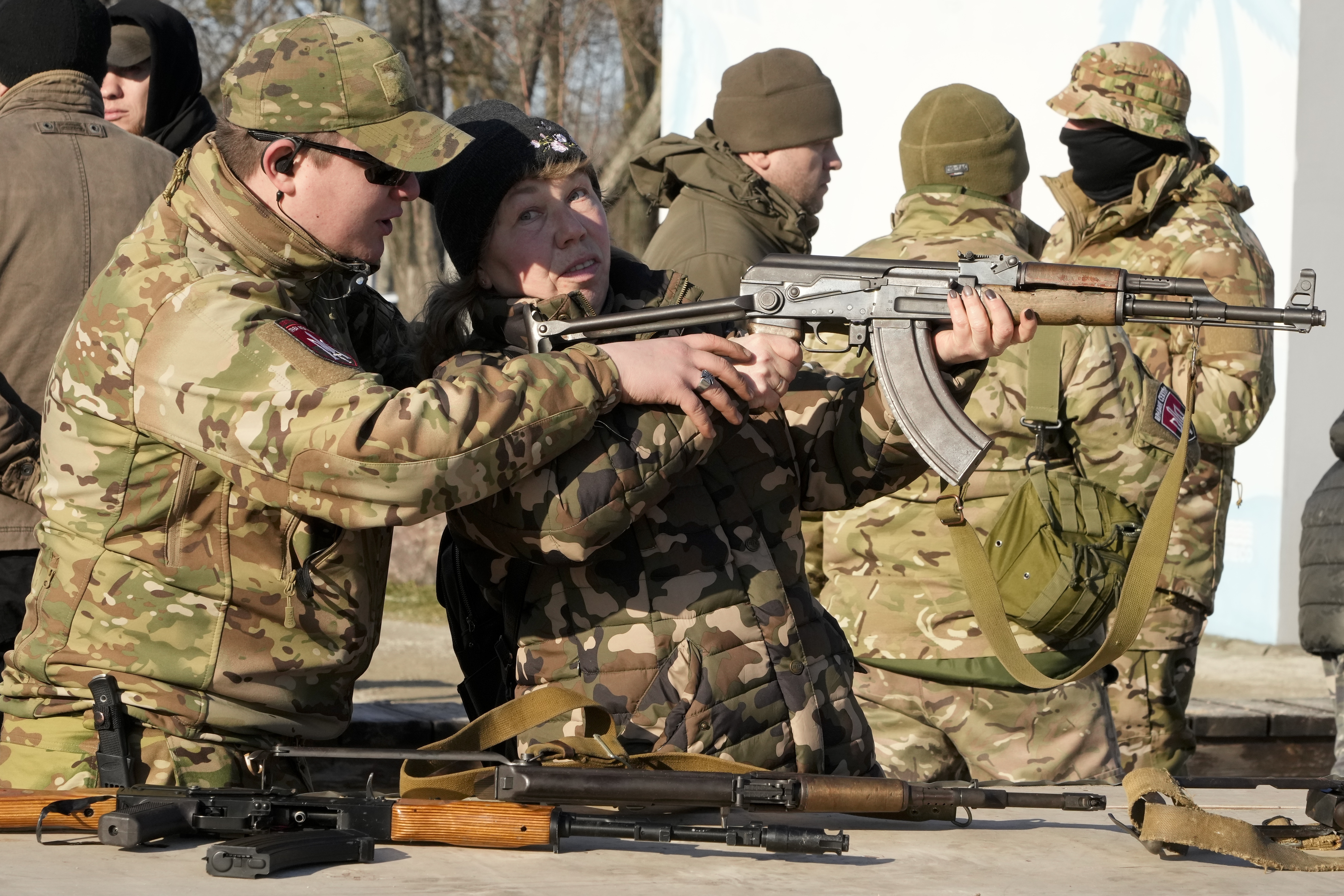 An instructor shows a woman how to use a Kalashnikov.