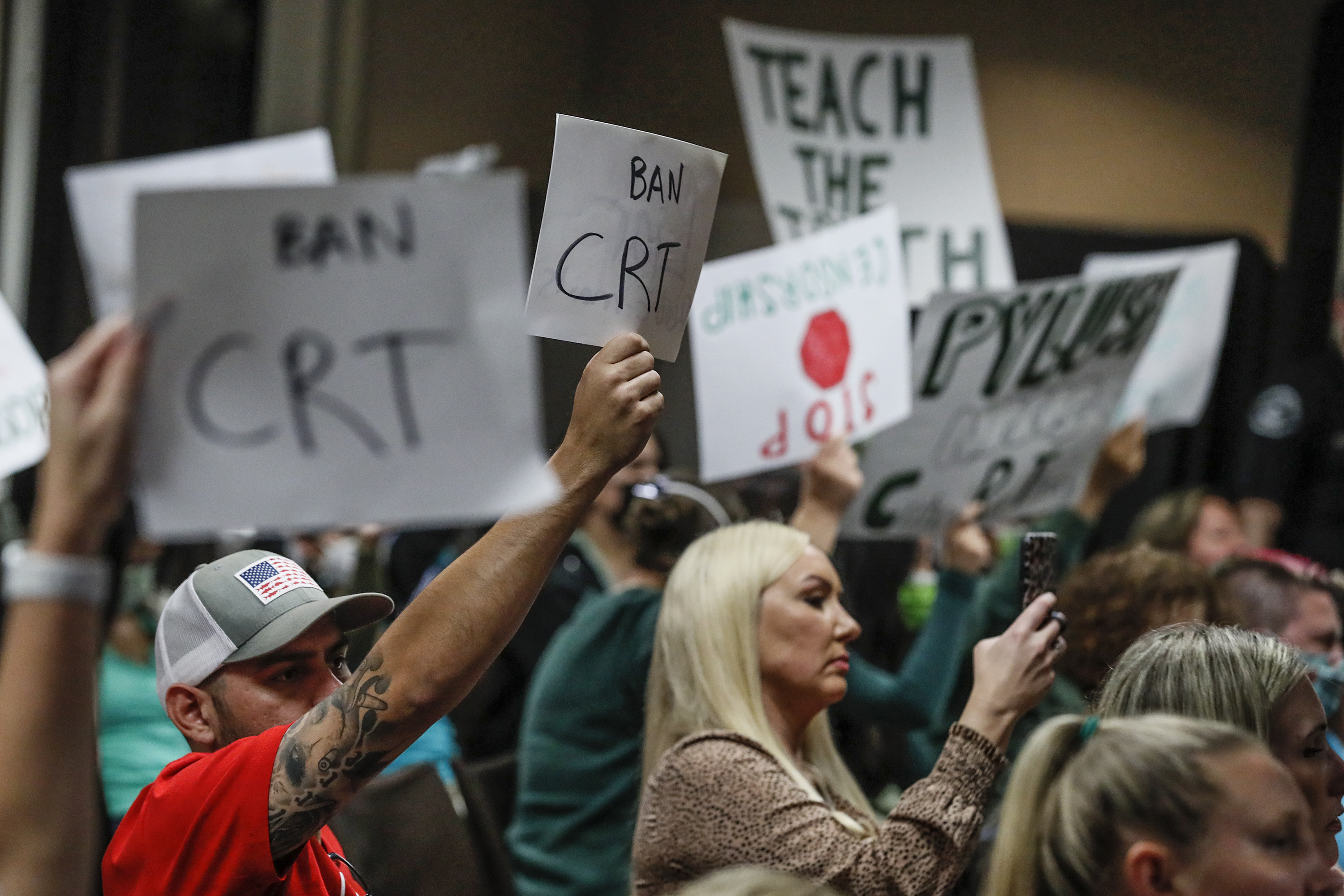 Parents hold banners that read "Ban CRT" at a school board meeting in Los Angeles