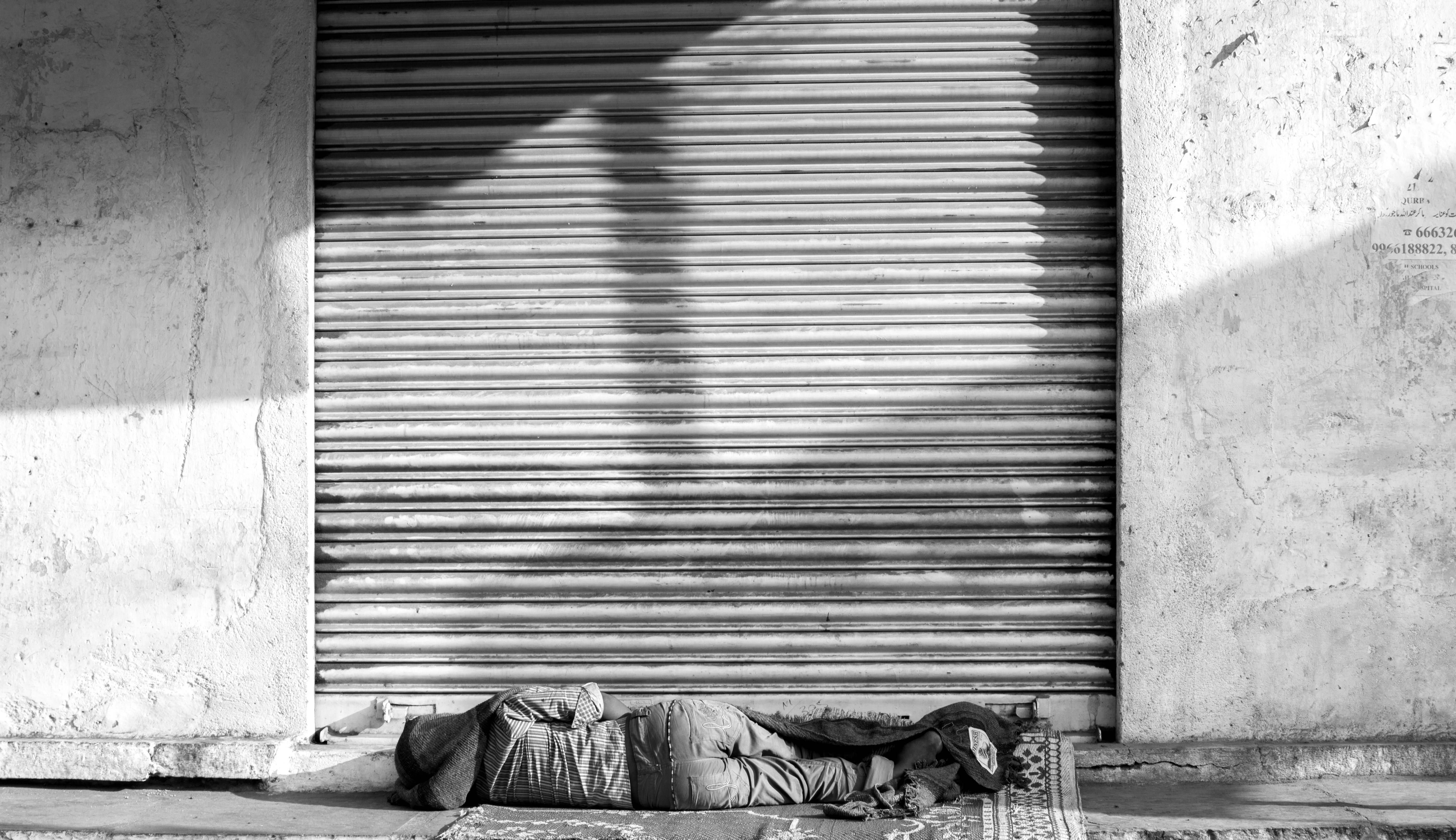 Black and white photo of a person sleeping on the street