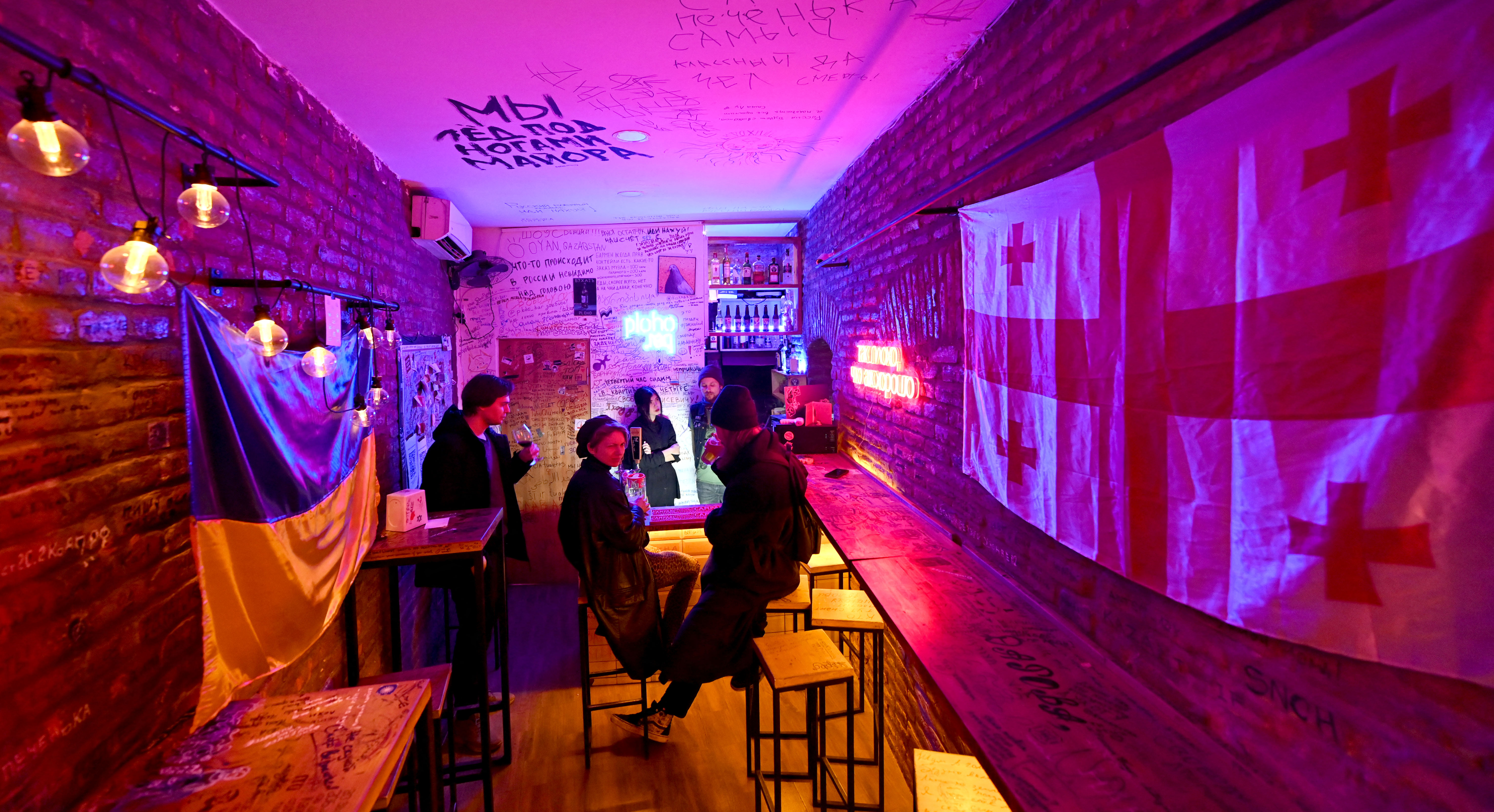 People in a bar in Tbilisi, next to the flags of Georgia and Ukraine