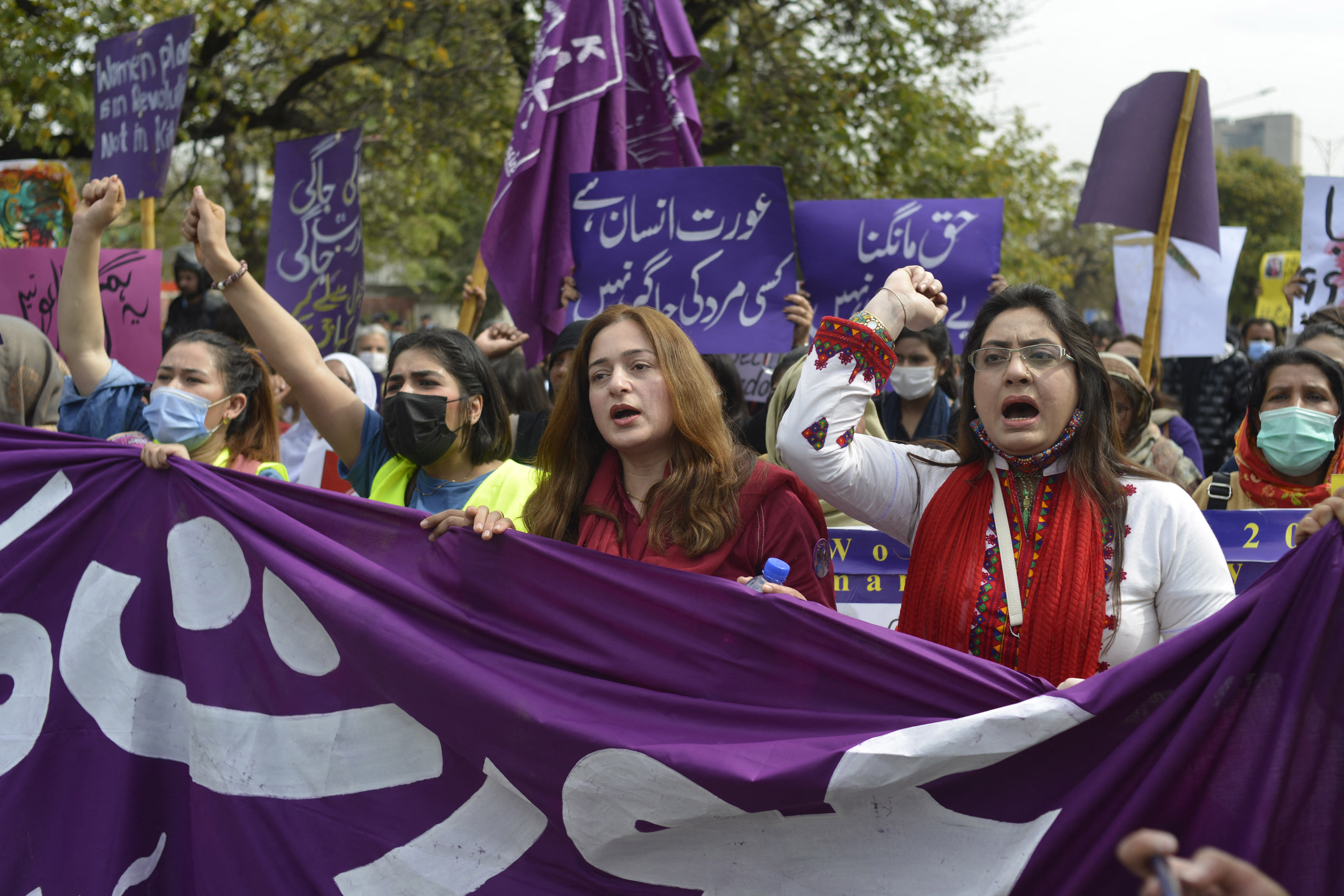 Aurat March protesters hold placards.
