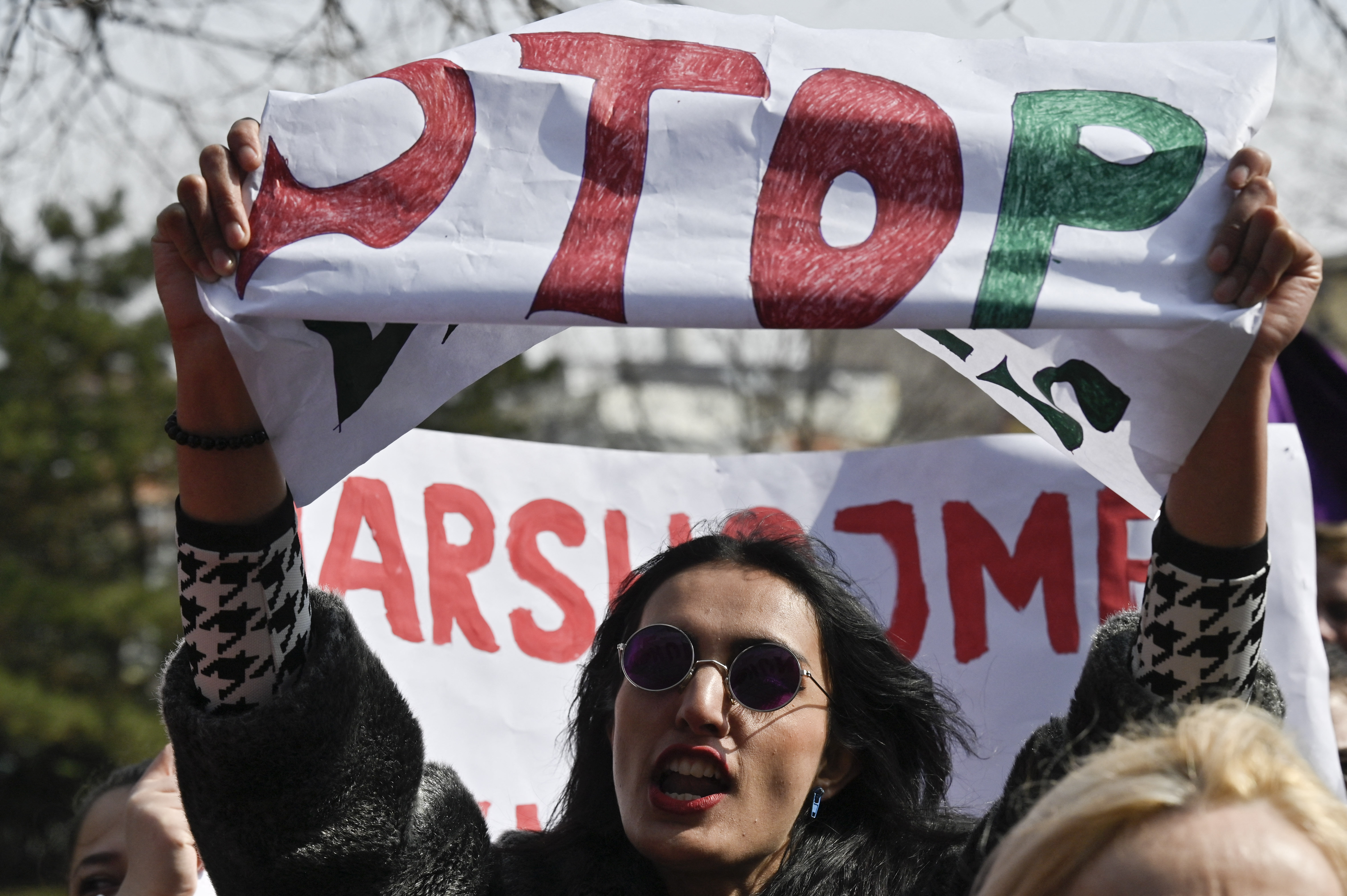 A woman shouts slogans and holds up a sign during a rally for gender equality and against violence towards women to mark the International Women's Day in Pristina