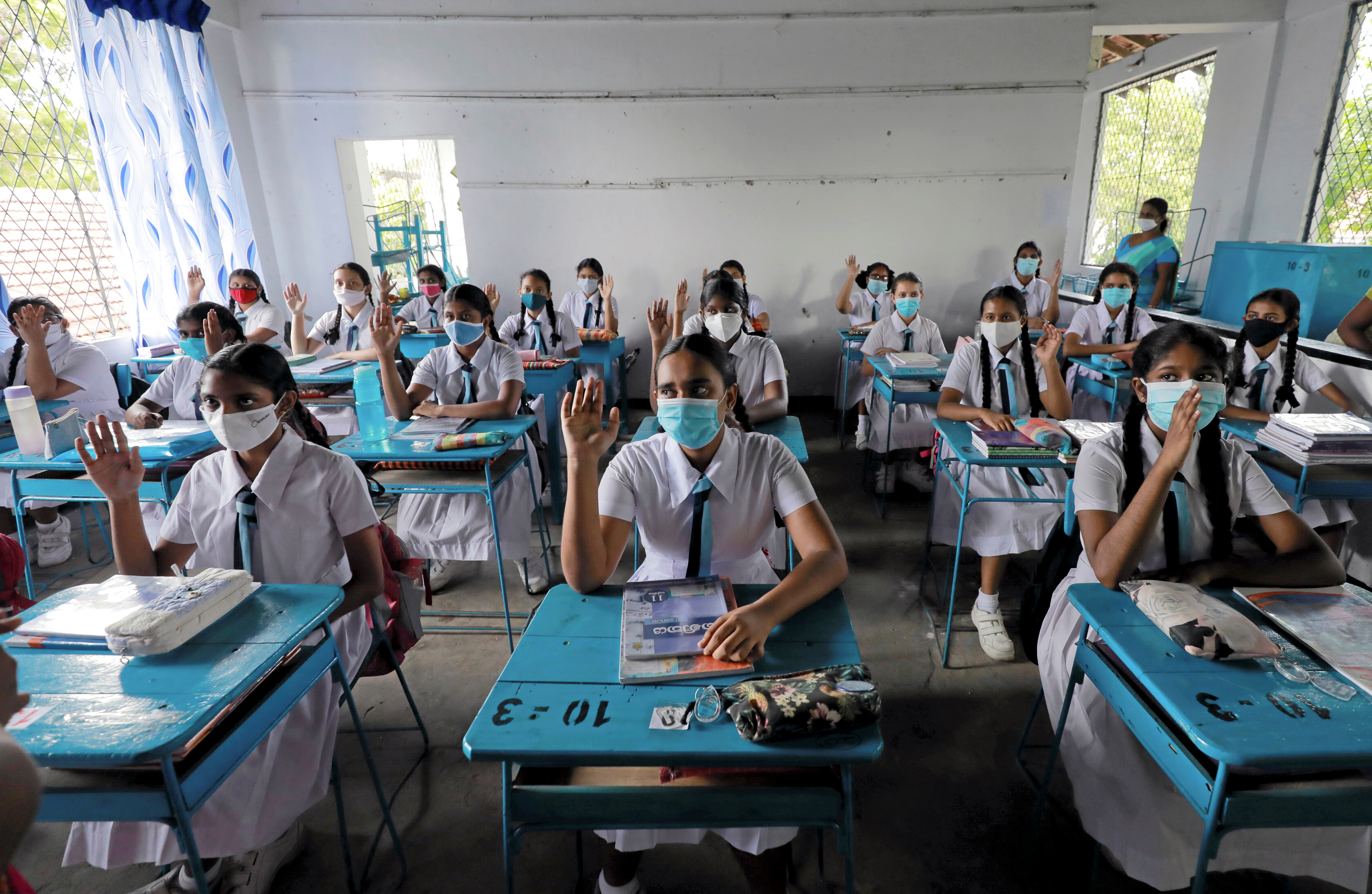 Students wearing protective face masks practice keeping a one meter distance as they attend a maths lesson inside a class room on the first day at Vidyakara college, which re-opened after almost two months of lock-down amidst concerns about the spread of coronavirus disease (COVID-19), in Colombo, Sri Lanka July 6, 2020.