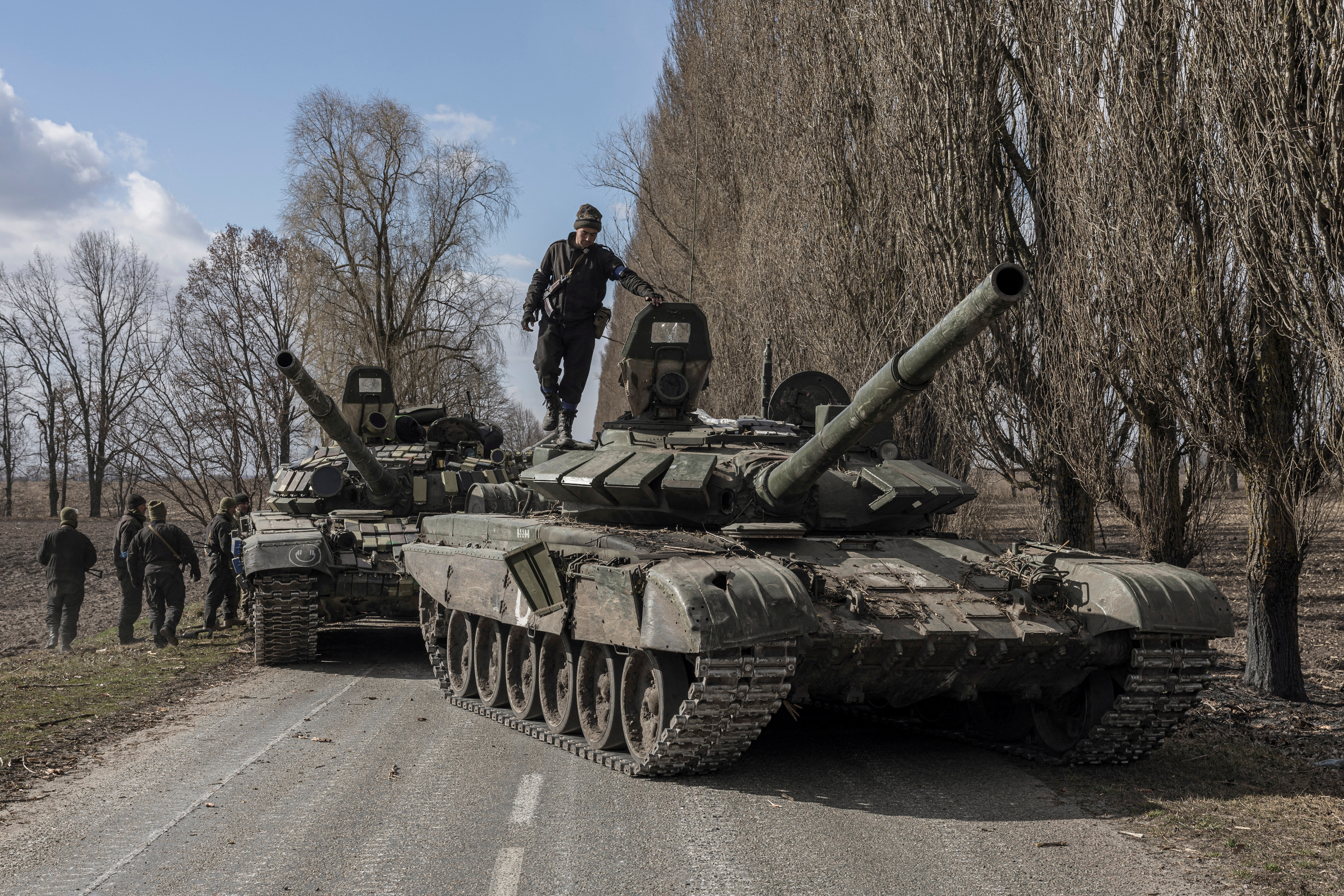A Ukranian serviceman stands on top of a Russian tank captured after fighting with Russian troops