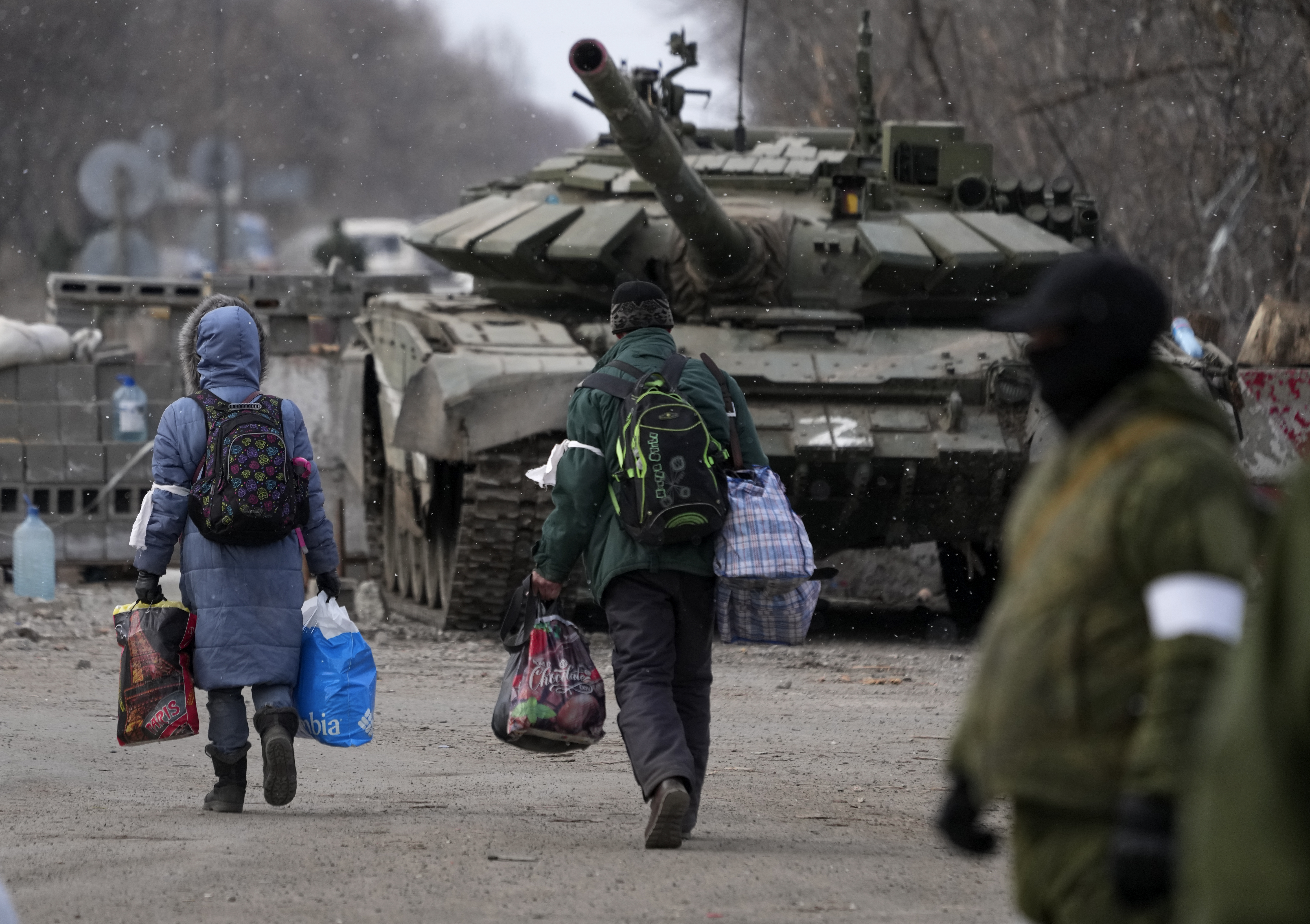 Civilians trapped in Mariupol city walk in front of a tank as they are evacuated.